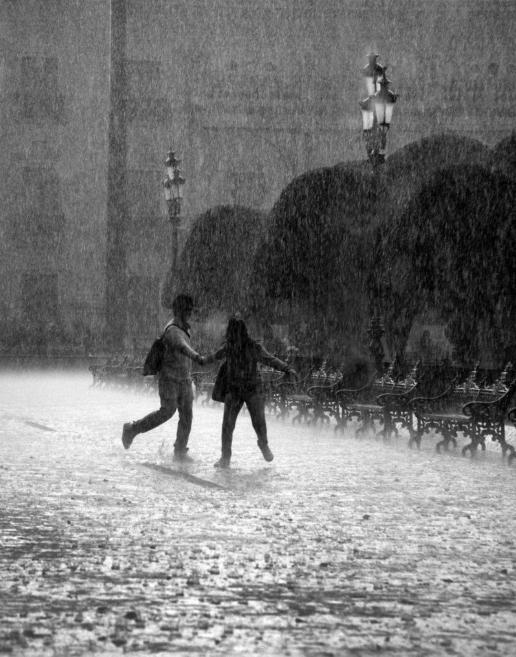 兩個人在暴雨中一起在廣場上奔跑。