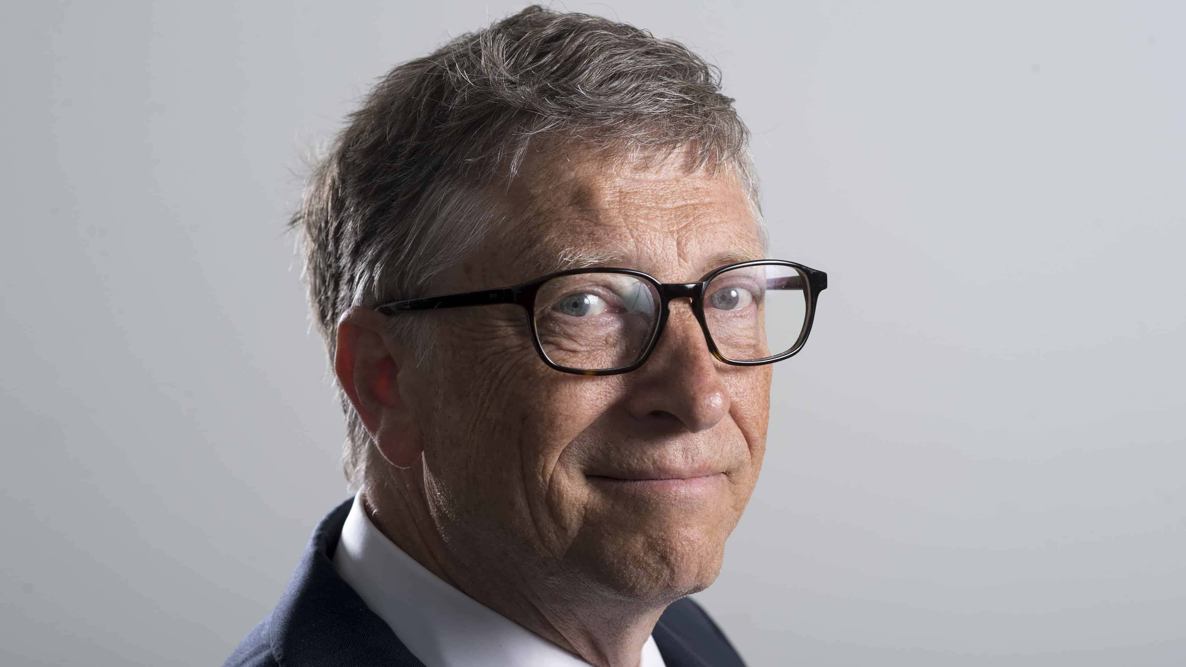 Bill Gates 桌布 壁紙 — 灰髮戴黑框眼鏡男士的特寫肖像，在純淺灰色背景前輕柔微笑。