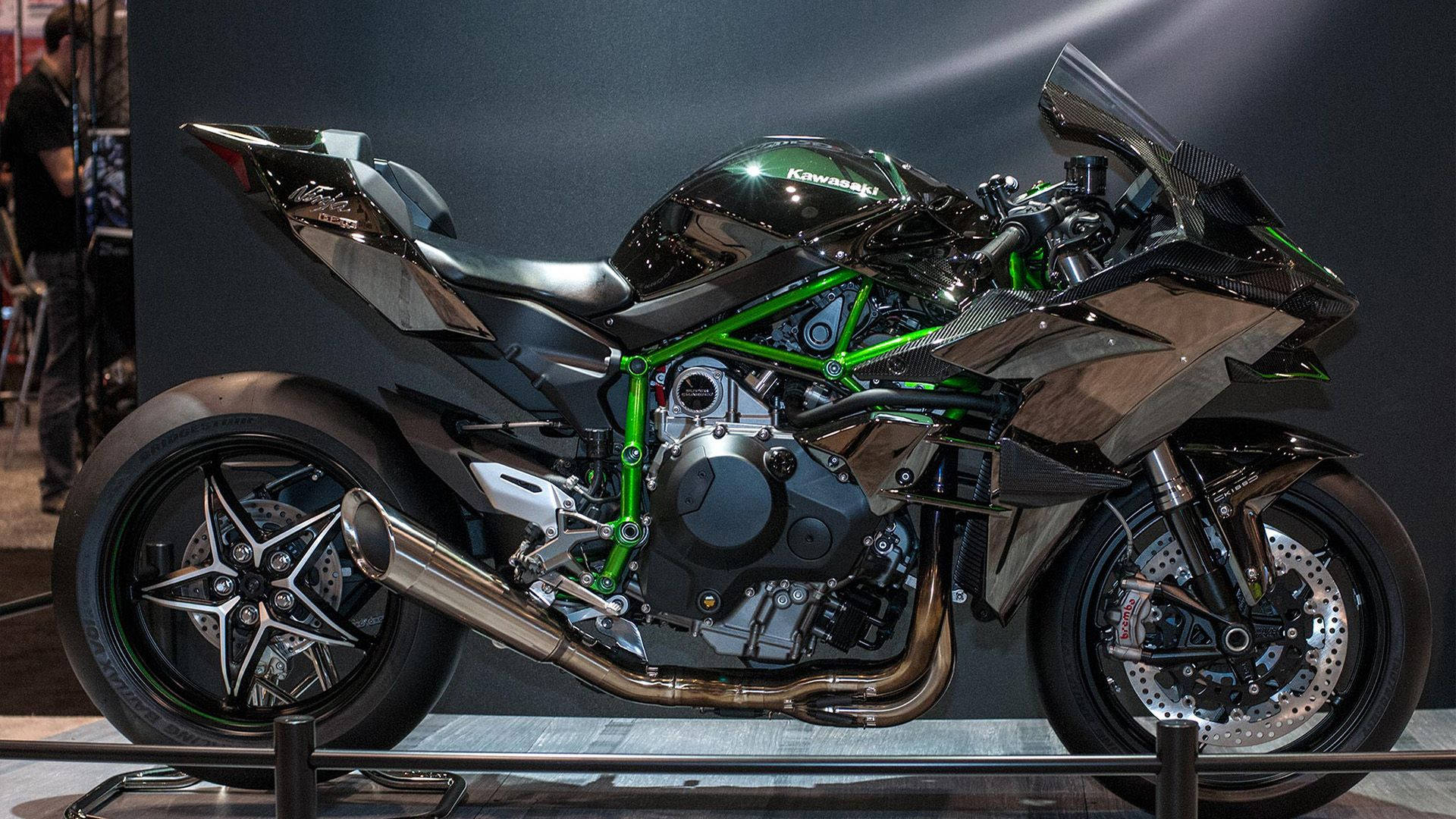 展示中的黑色和綠色 Kawasaki 運動摩托車，帶有外露引擎和碳纖維部件。