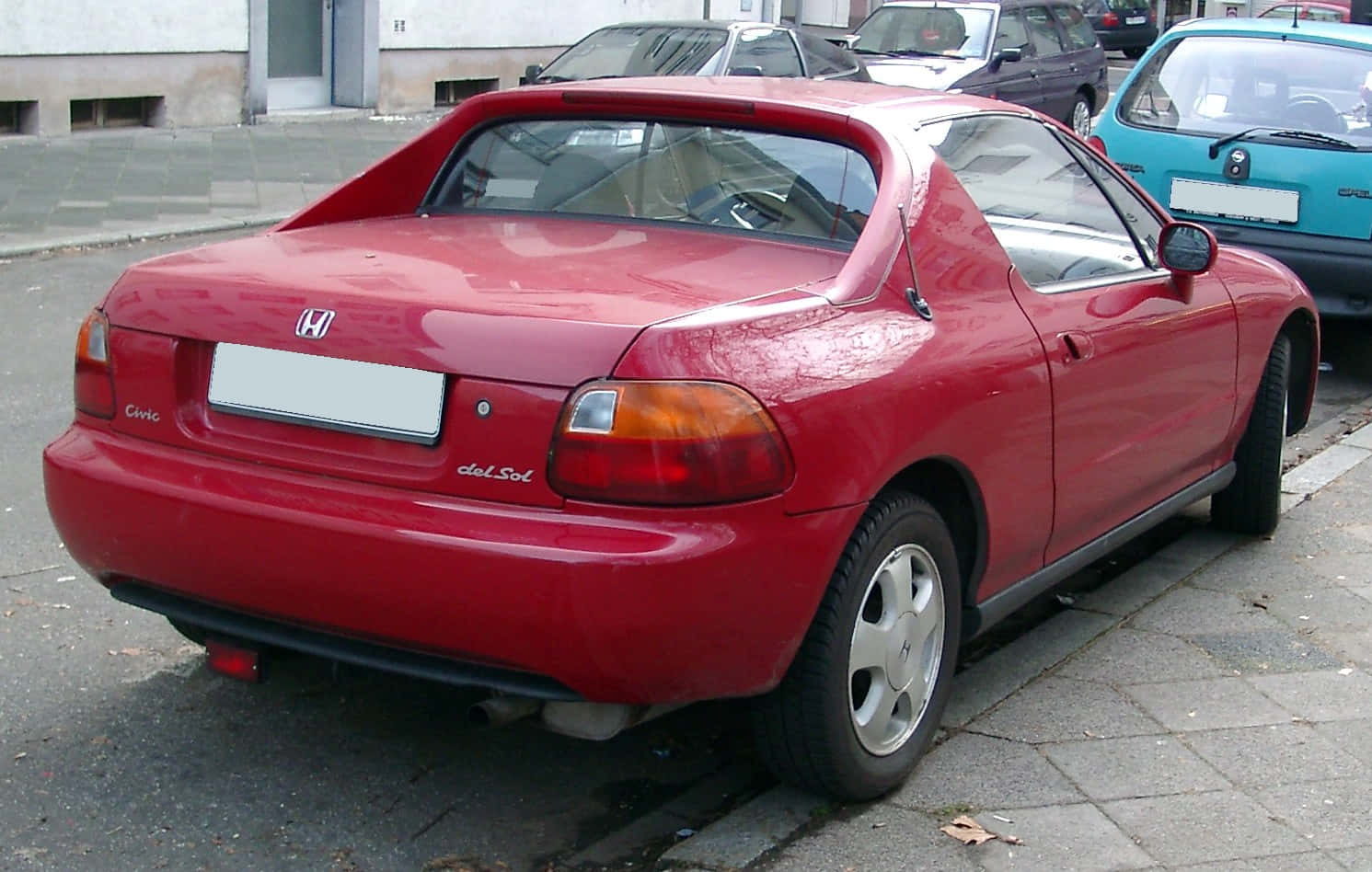 炫目的紅色本田Civic Del Sol展示 壁紙 — 一架鮮紅色的本田Civic del Sol停泊在鋪砌的街道上，附近有其他車輛。