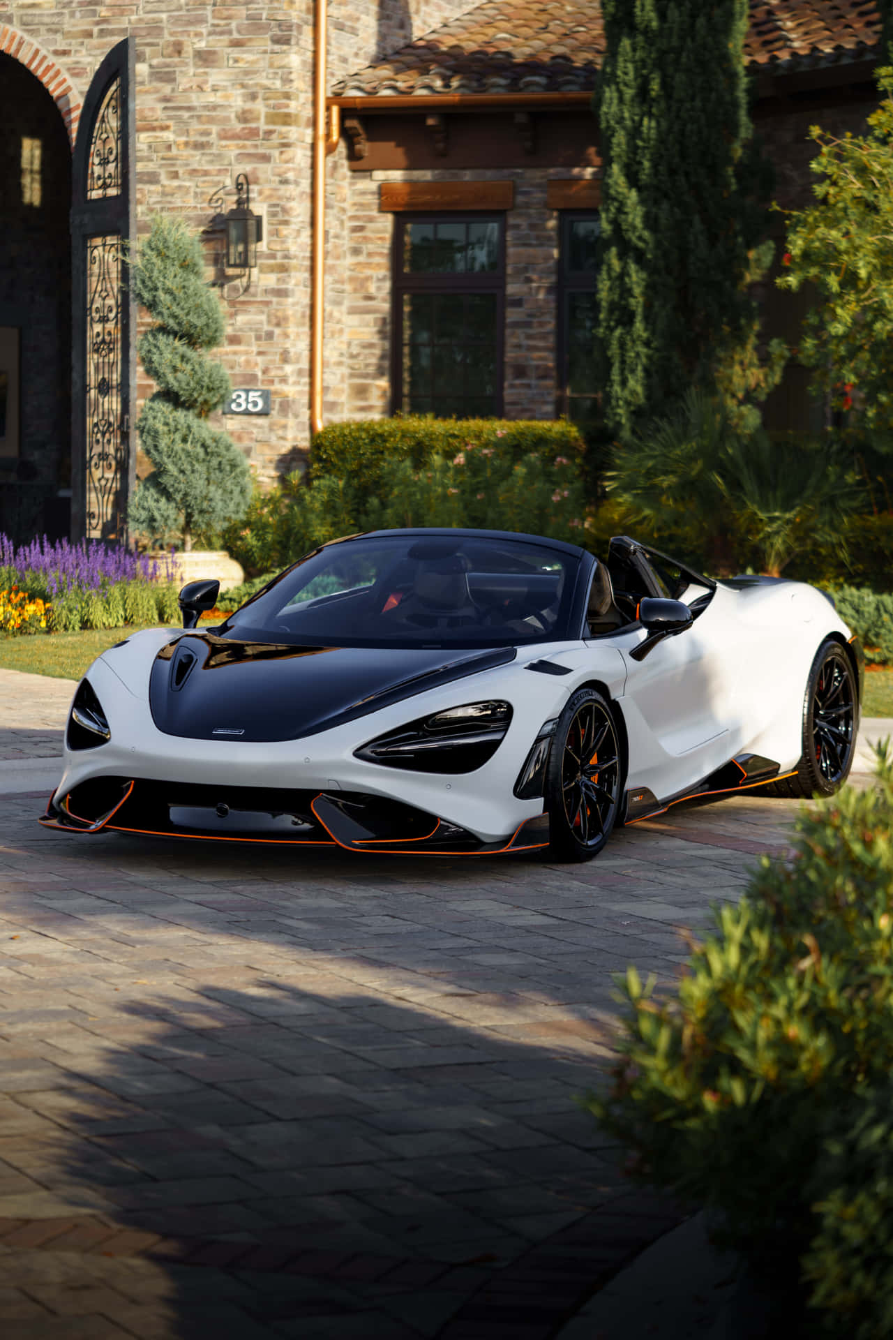 白色McLaren Speedtail敞篷車在日落時停在豪華石砌豪宅前。