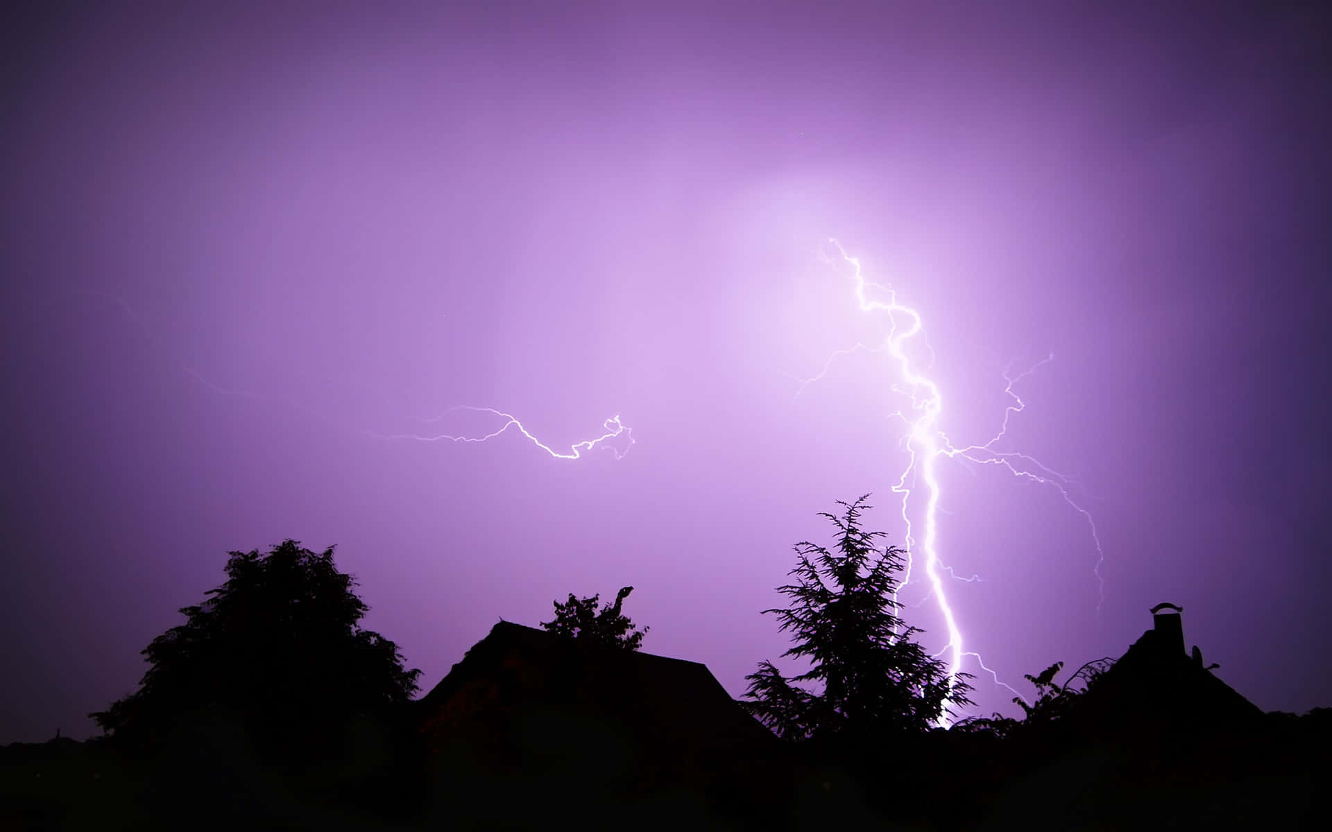 閃電擊中屋頂和樹木，背景是紫色暴風雨天空。
