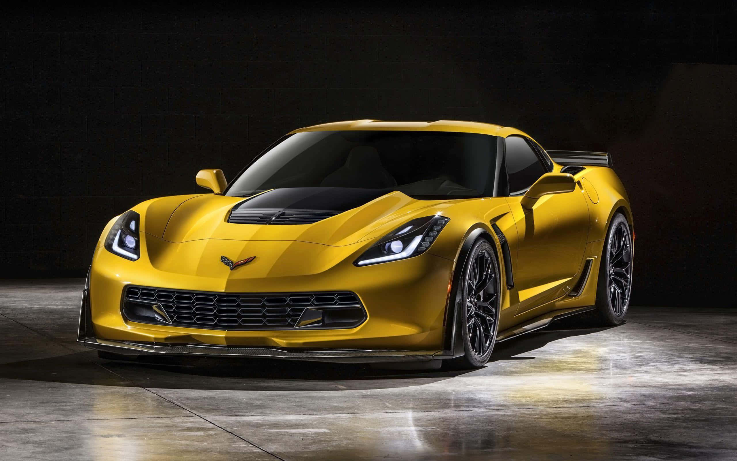 炫目雪佛蘭克爾維特 Z06 駛於公路上 壁紙 — 一輛閃亮的黃色雪佛蘭克爾維特跑車在黑暗的攝影棚背景下，搭配反射性混凝土地板，被戲劇性地照亮。
