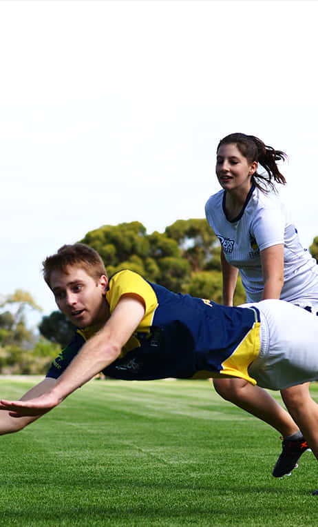 炫酷Android Ultimate Frisbee數位藝術作品 壁紙 — 兩名穿著運動裝備的運動員在明亮的天空下，在充滿活力的綠色場地上潛水和追逐。