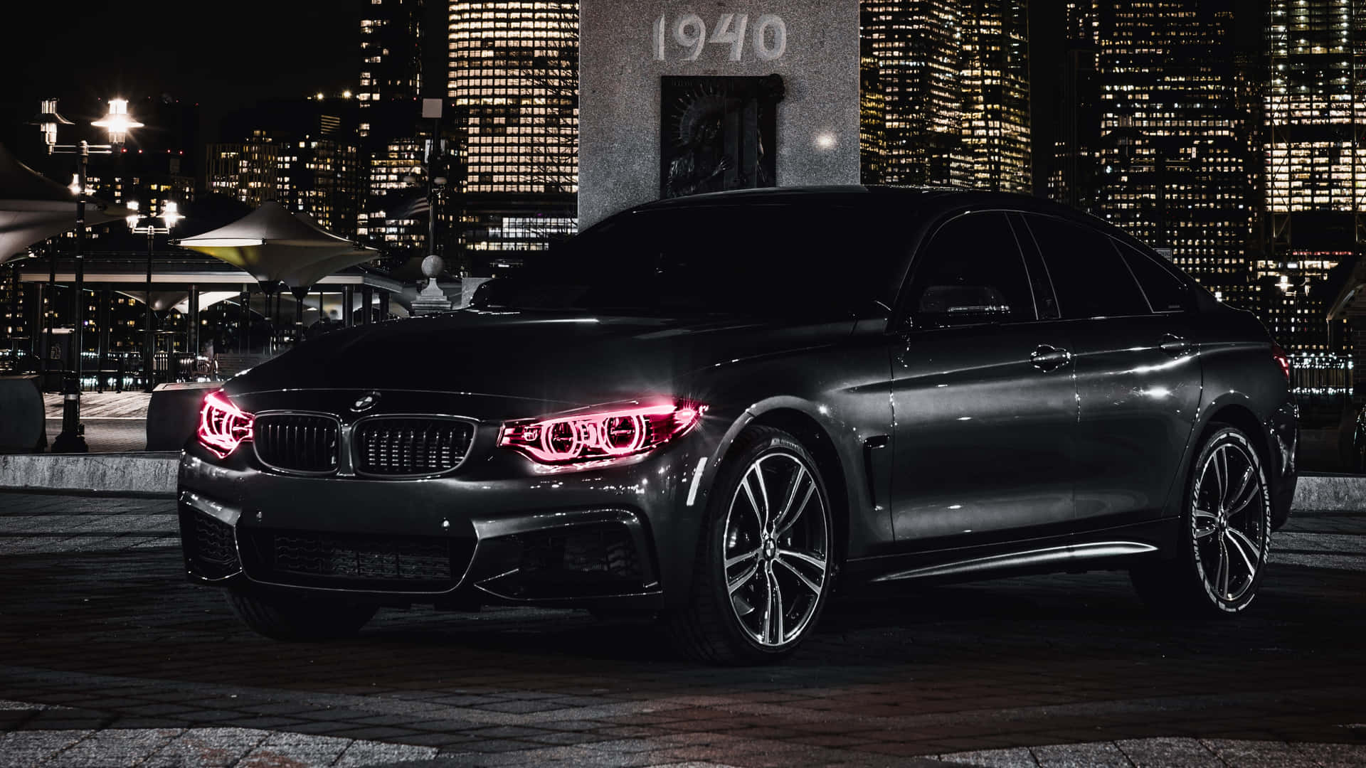黑色BMW轎車，紅色車頭燈，夜間停在城市中。