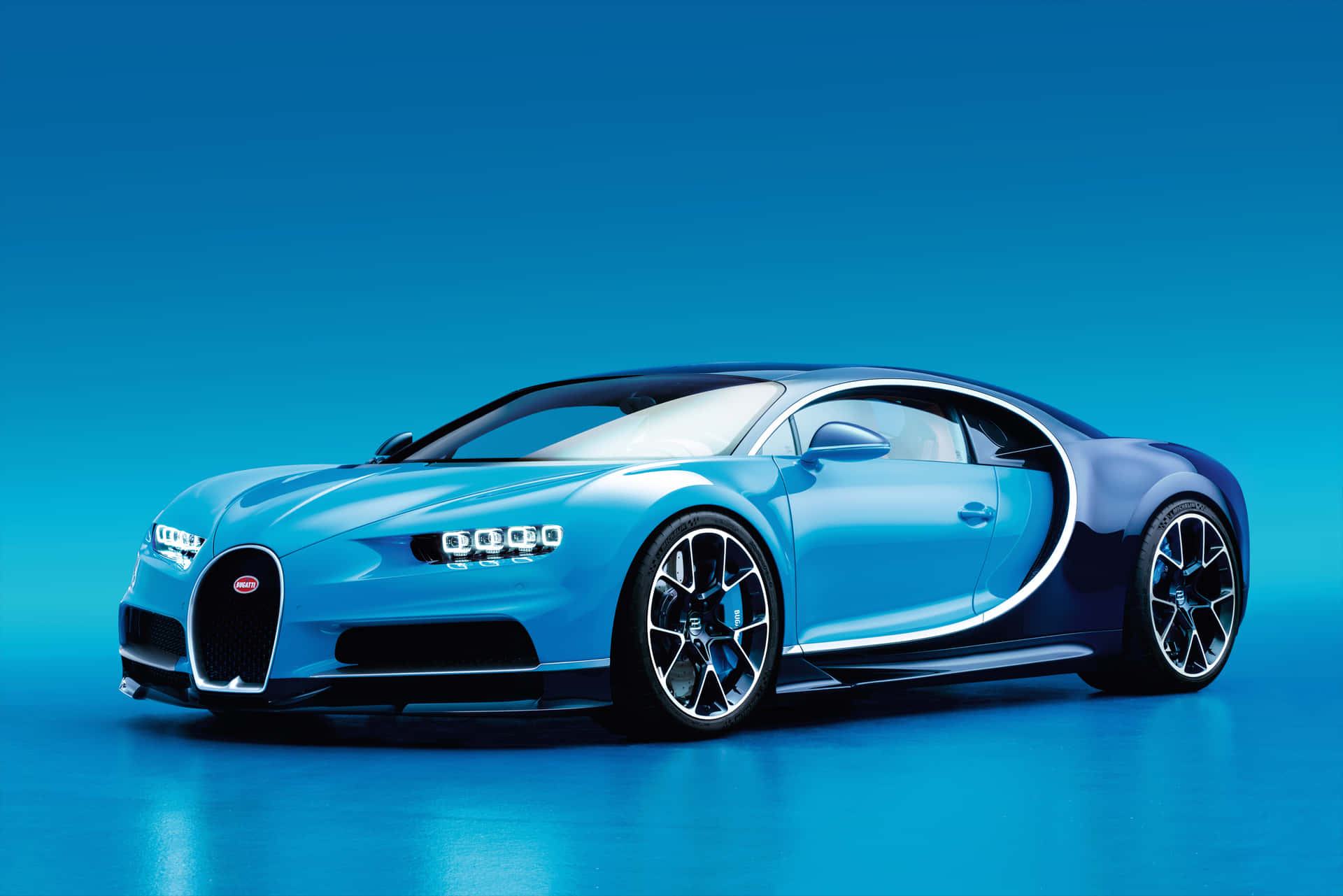一輛藍色Bugatti Chiron跑車在攝影棚內，地板有反射效果。