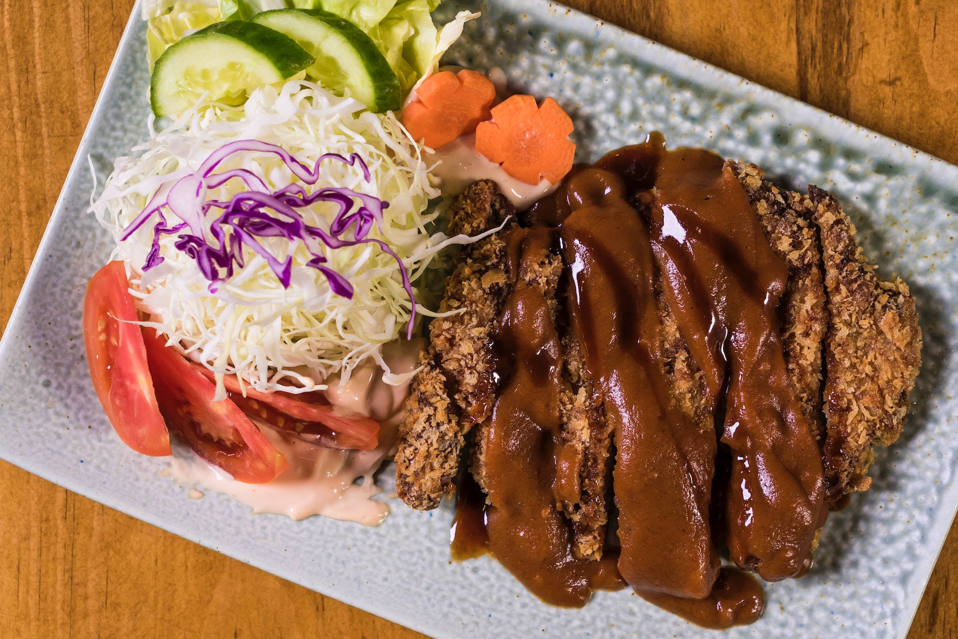 酥脆炸肉排配棕色醬汁和新鮮沙律，放在有紋理的碟子上。