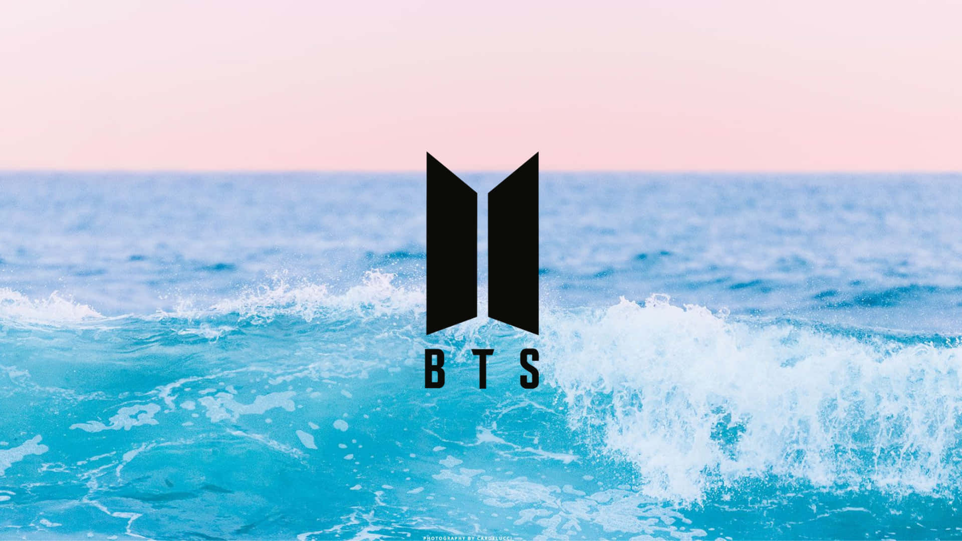 日落時分，BTS 標誌在翻騰的海浪之上