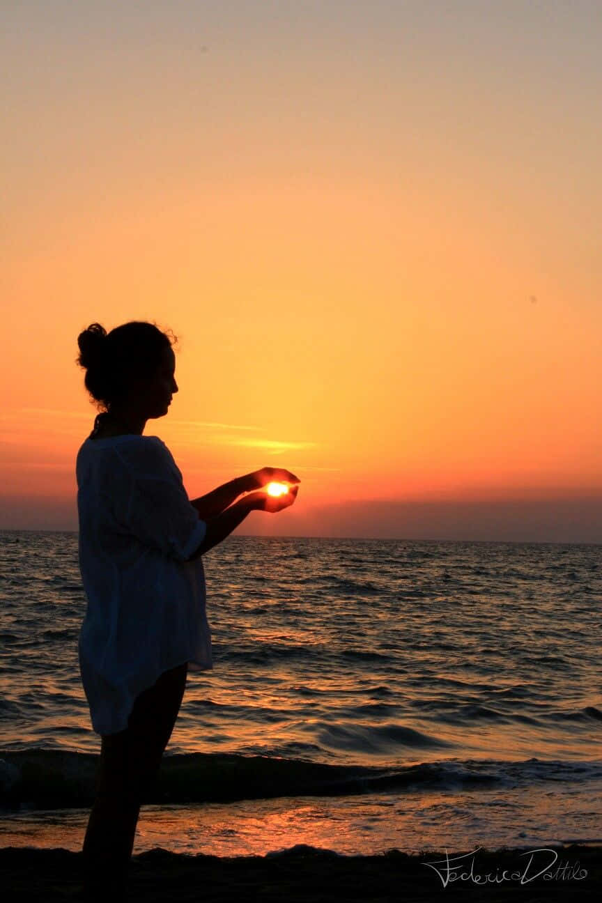 女人在海灘日落時舉著太陽