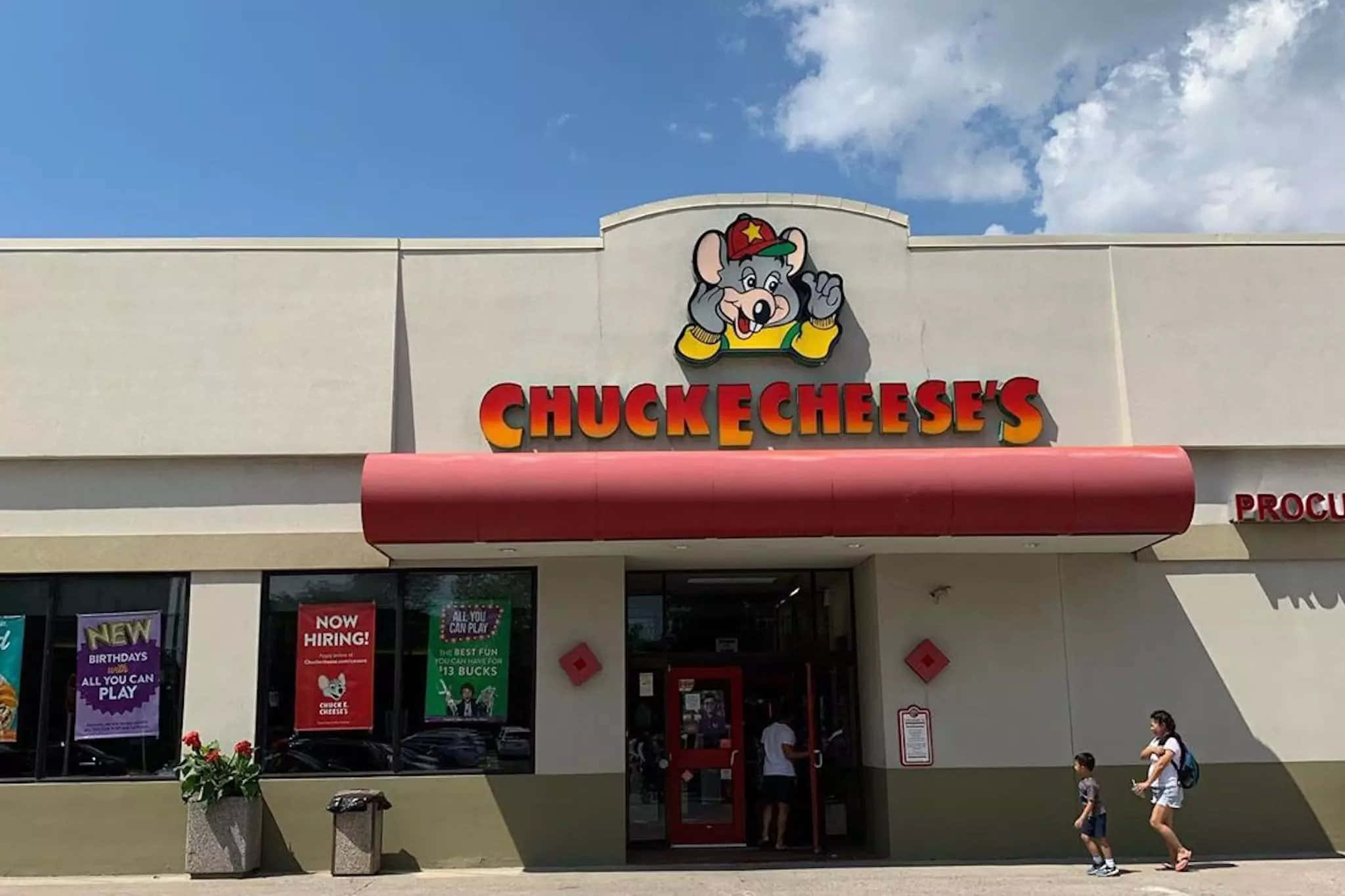 Chuck E Cheese's遊戲機餐廳，卡通老鼠吉祥物和進入的人們。
