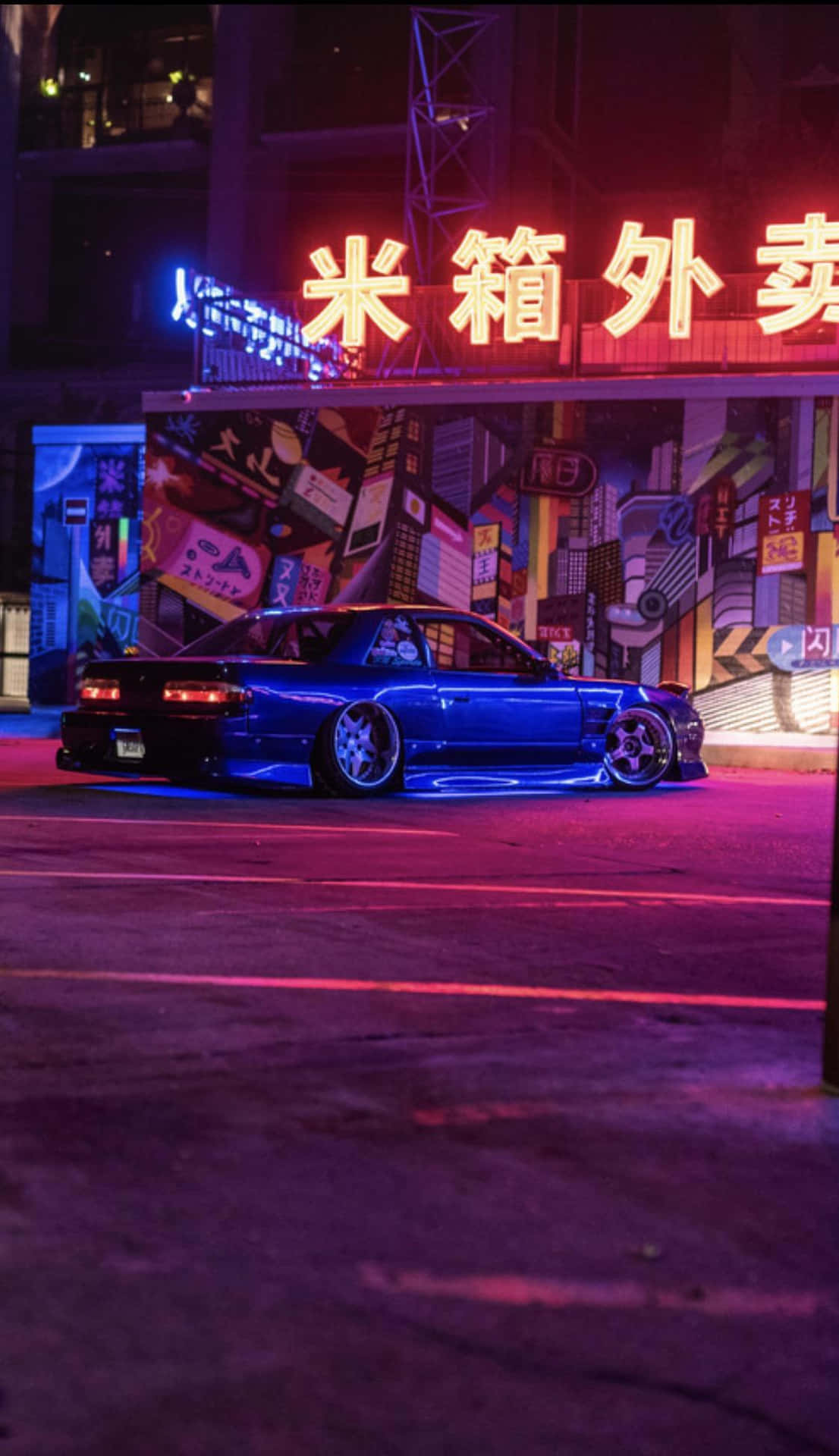 藍色跑車停放在城市夜晚發光的霓虹招牌下。