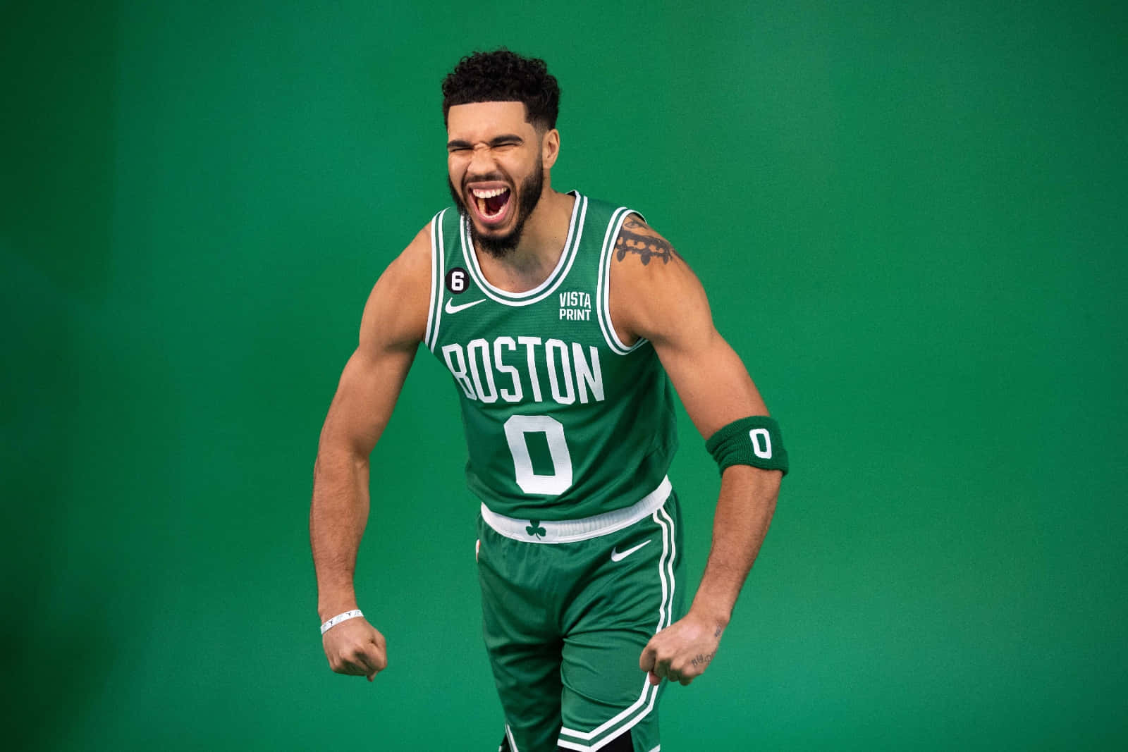 為波士頓塞爾提克隊攀上NBA巔峰而準備！ 壁紙 — 一名身穿綠色波士頓塞爾特人球衣的籃球運動員在純綠色背景下勝利咆哮。