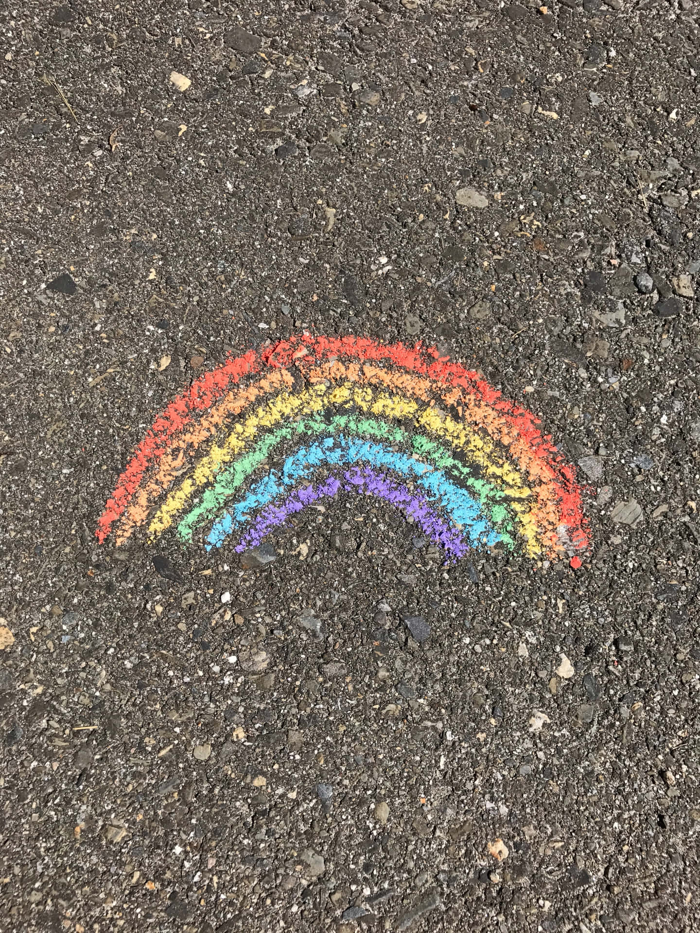 在深色瀝青上繪製的彩色粉筆彩虹。