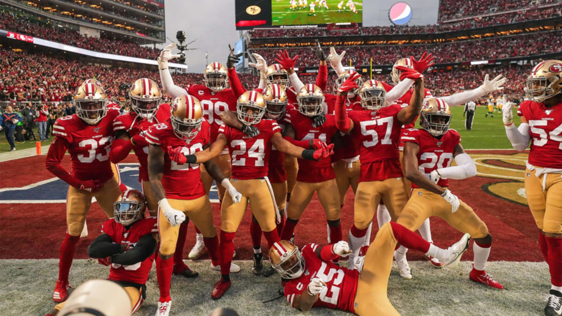 美式足球隊在球場上高舉雙臂慶祝勝利