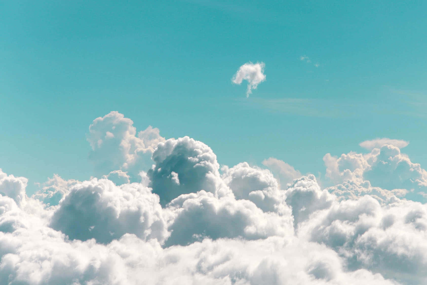 以充滿活力的綠松色天空為背景的蓬鬆白雲空中景觀。