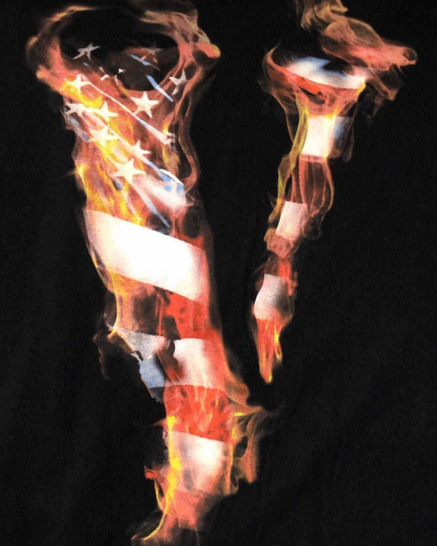 烈焰美國風 VLONE 標誌 壁紙 — 美國國旗在黑色背景上燃燒，伴有旋轉的煙霧和發光的餘燼。