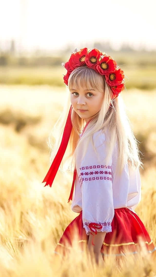 穿著傳統服飾的少女戴著紅色花冠，站在夕陽下的金色麥田裡。