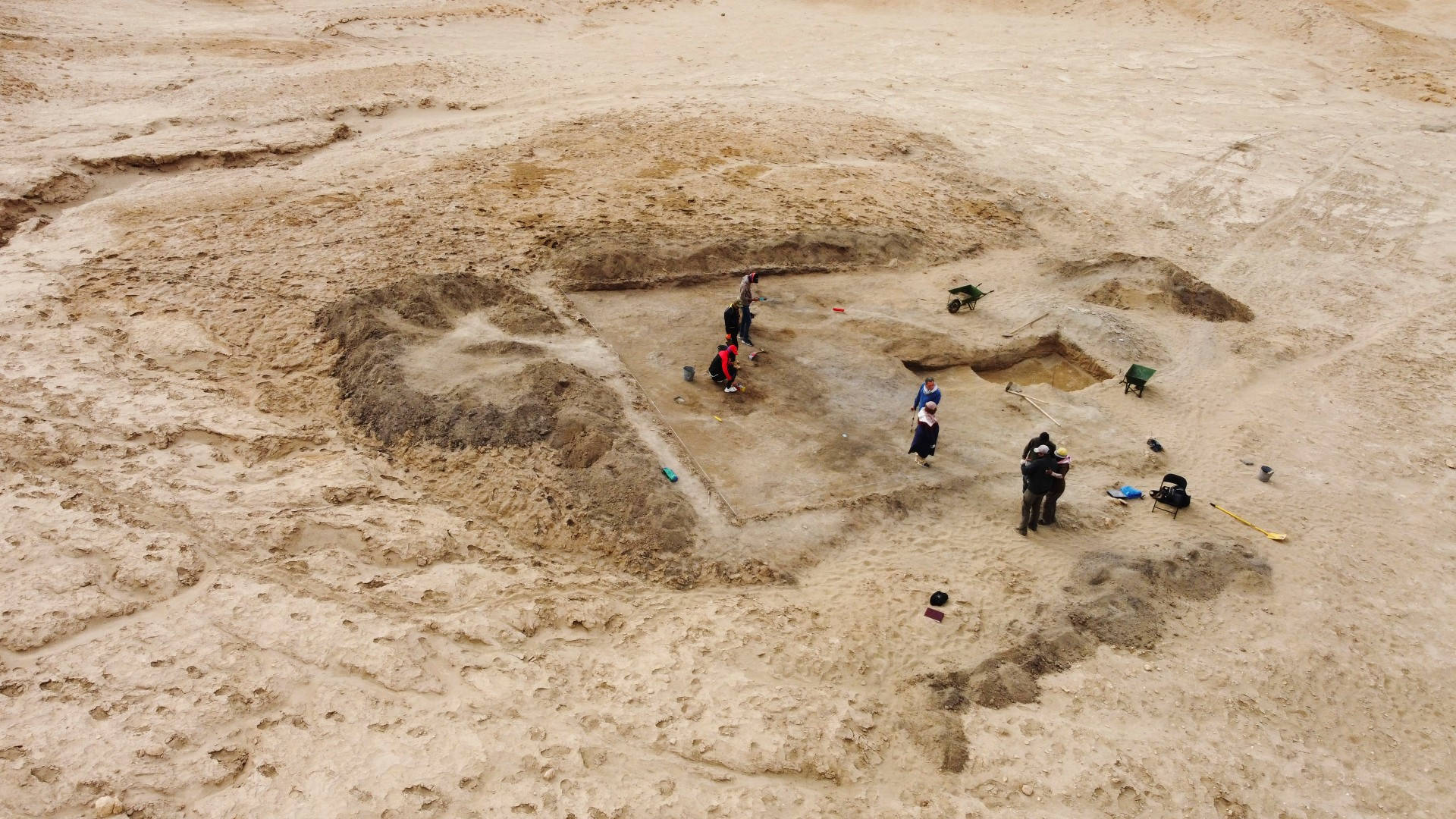 考古學家在沙地田野中處理古代圓形土方工程。