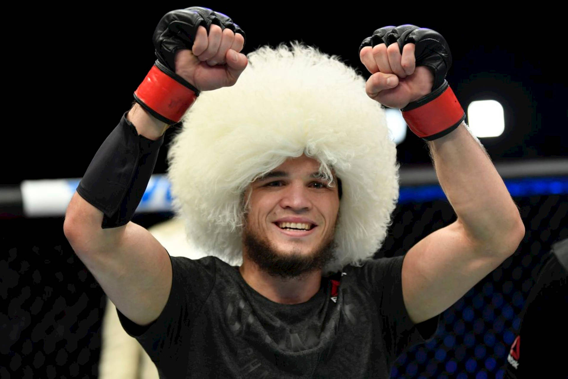 戴毛茸茸帽子的MMA拳手在八角籠內高舉拳頭慶祝勝利。