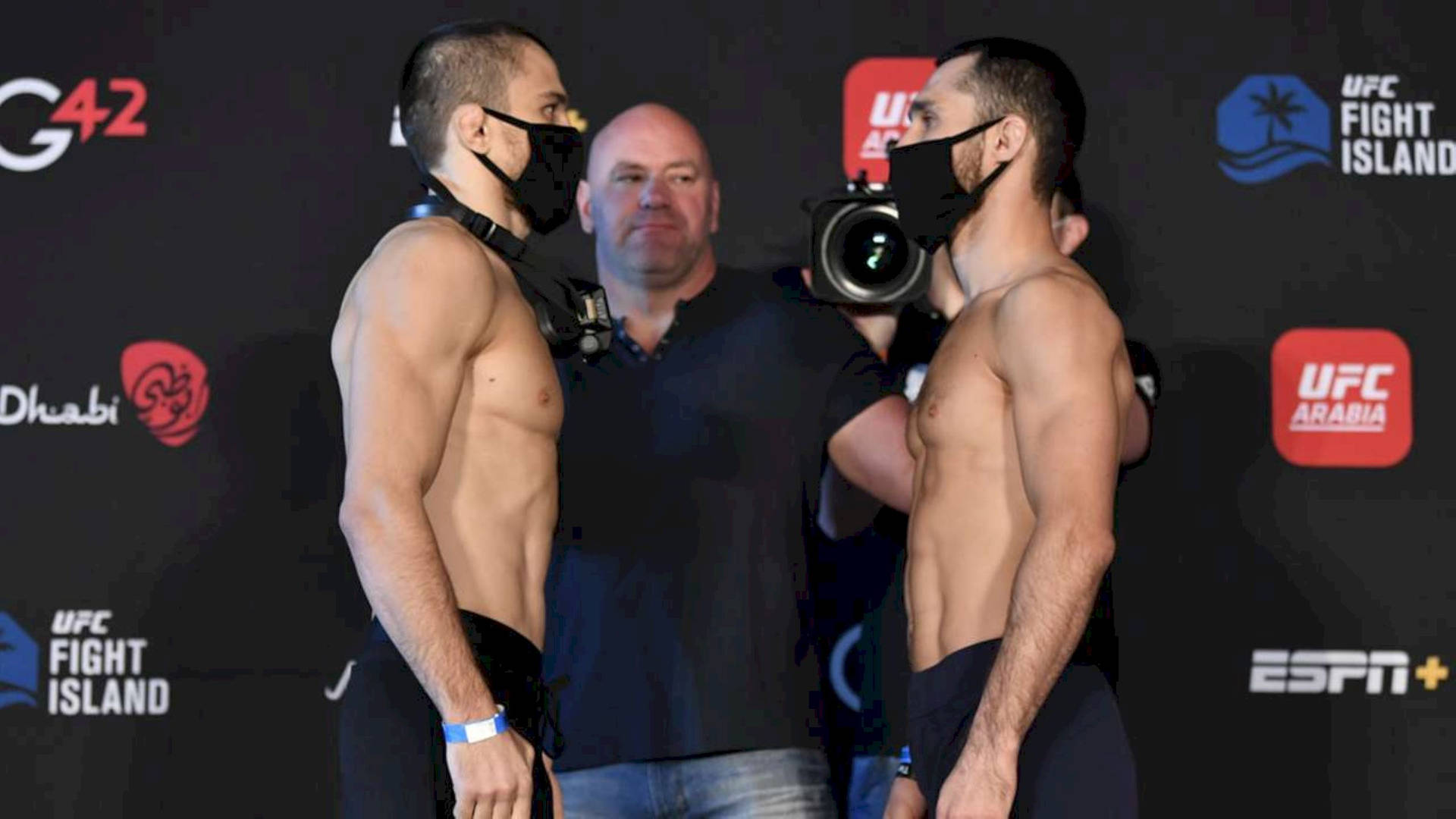 兩名赤裸上身的UFC拳手戴著口罩在稱重活動中對峙。