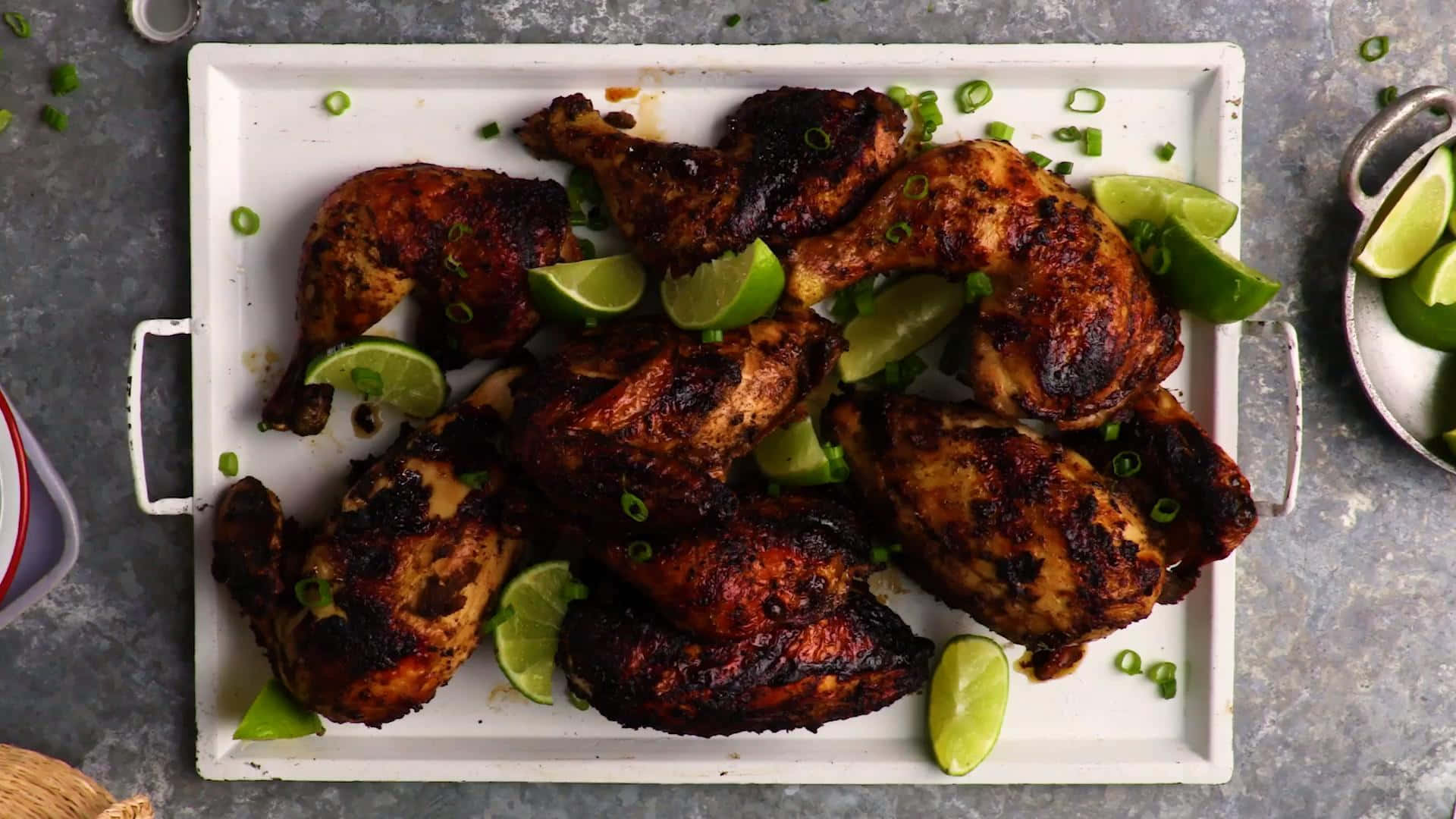 Blackened Chicken 桌布 壁紙 — 烤雞塊配青檸角同切碎嘅青蔥，放喺白色托盤上，灰色紋理背景。