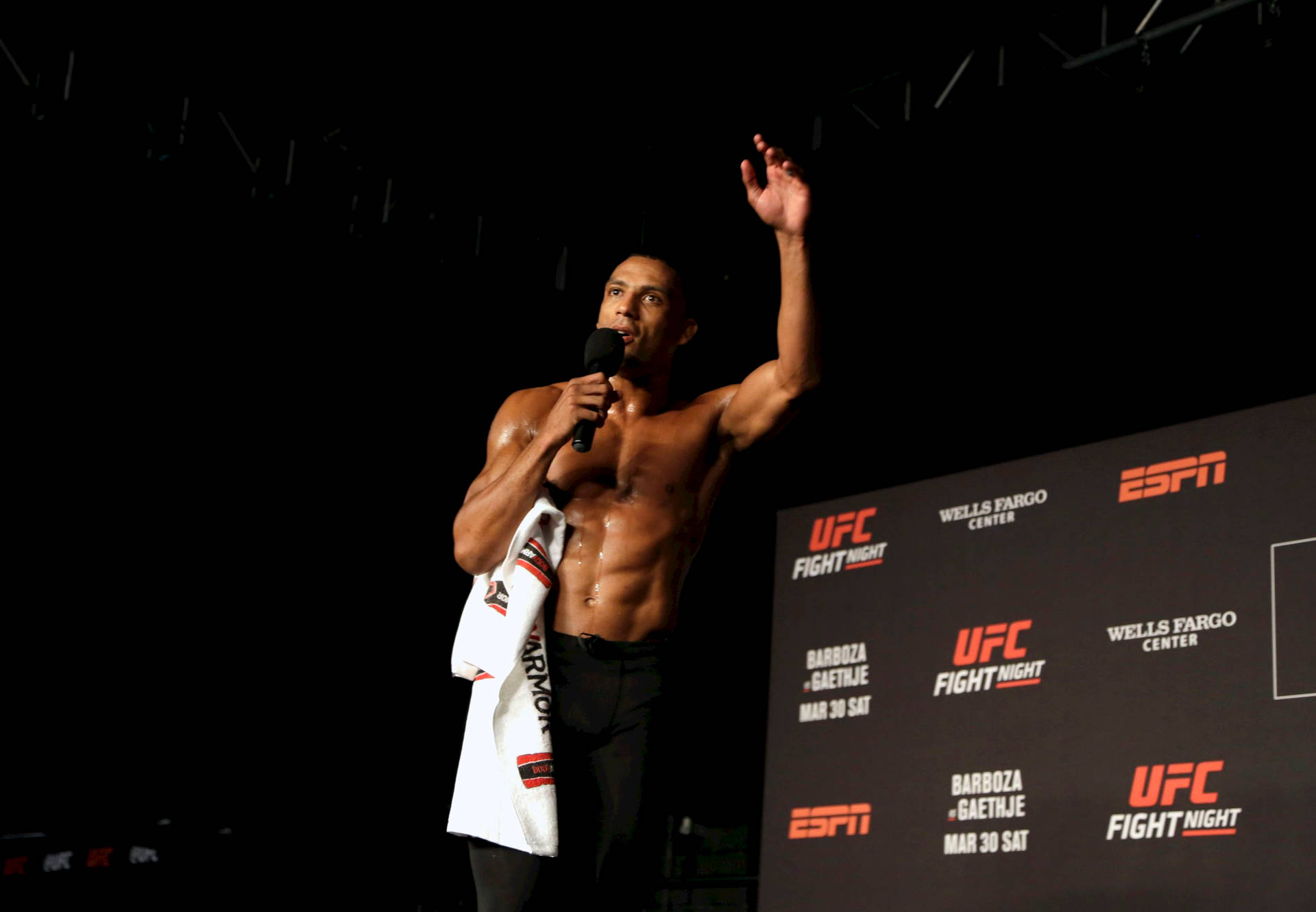 赤裸上身的拳手在UFC活動舞台上向人群揮手。