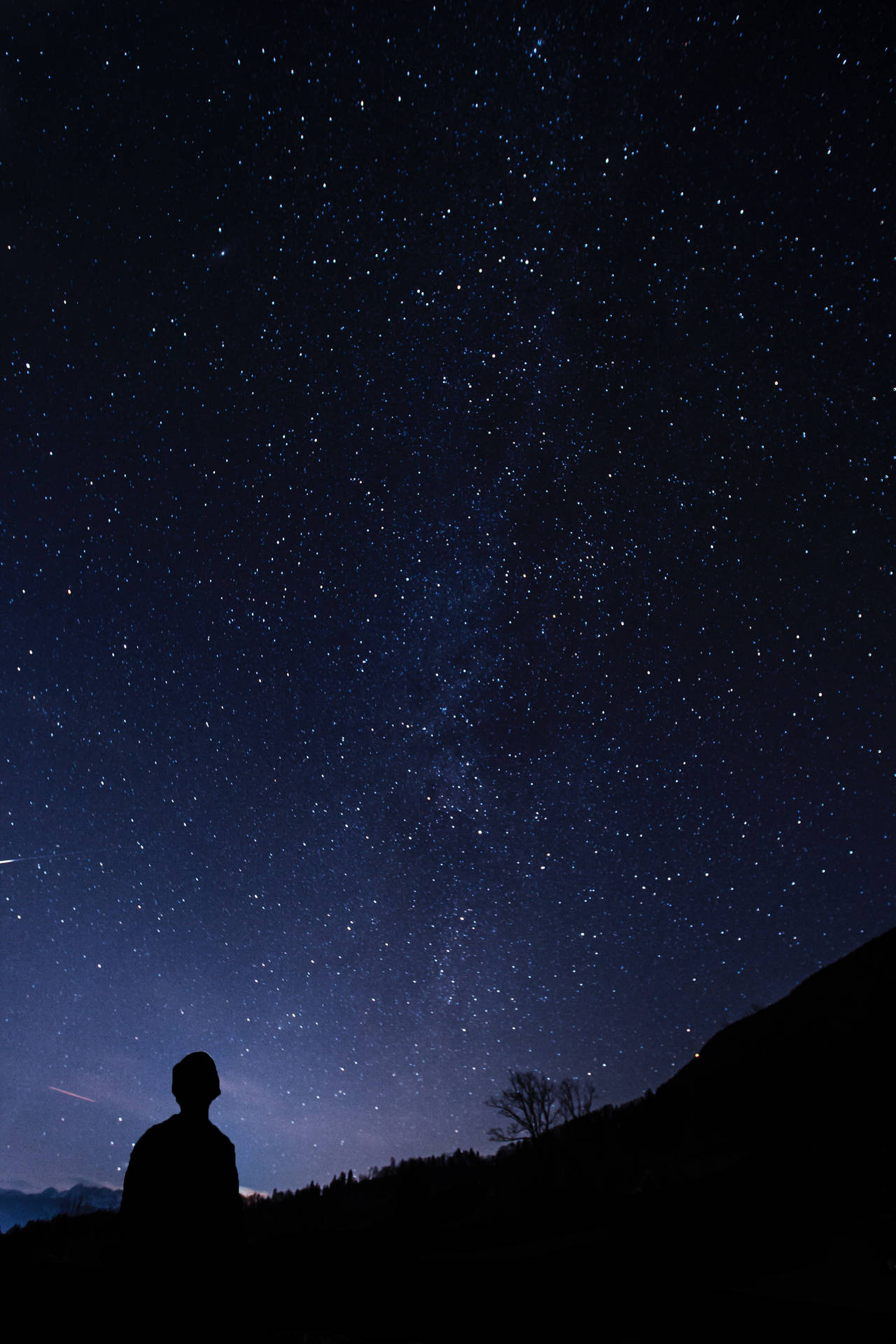 站在星空下山坡上的人