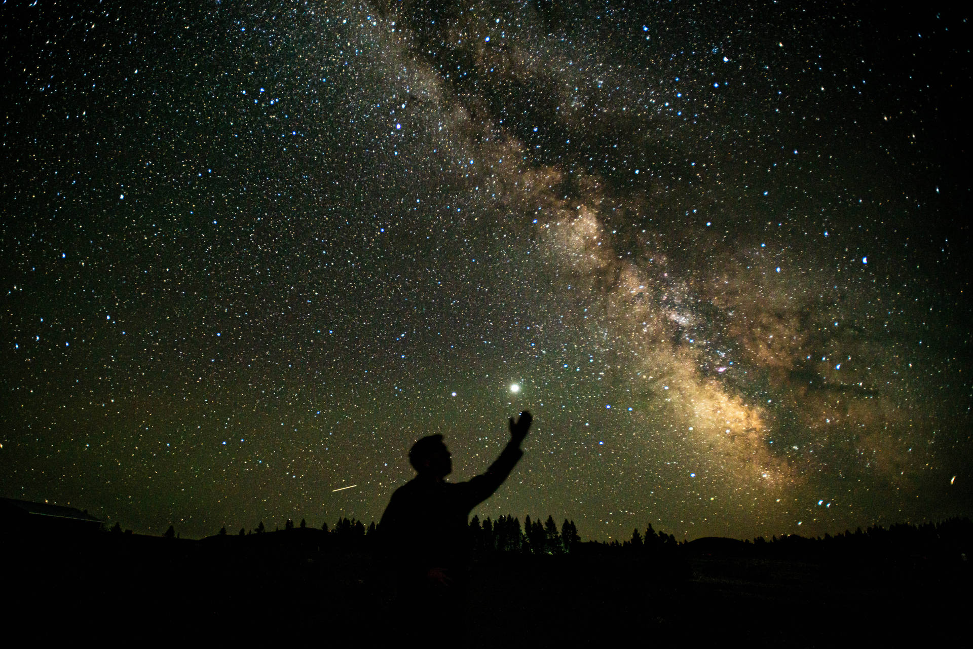 夜晚在星空下伸手的人，銀河可見