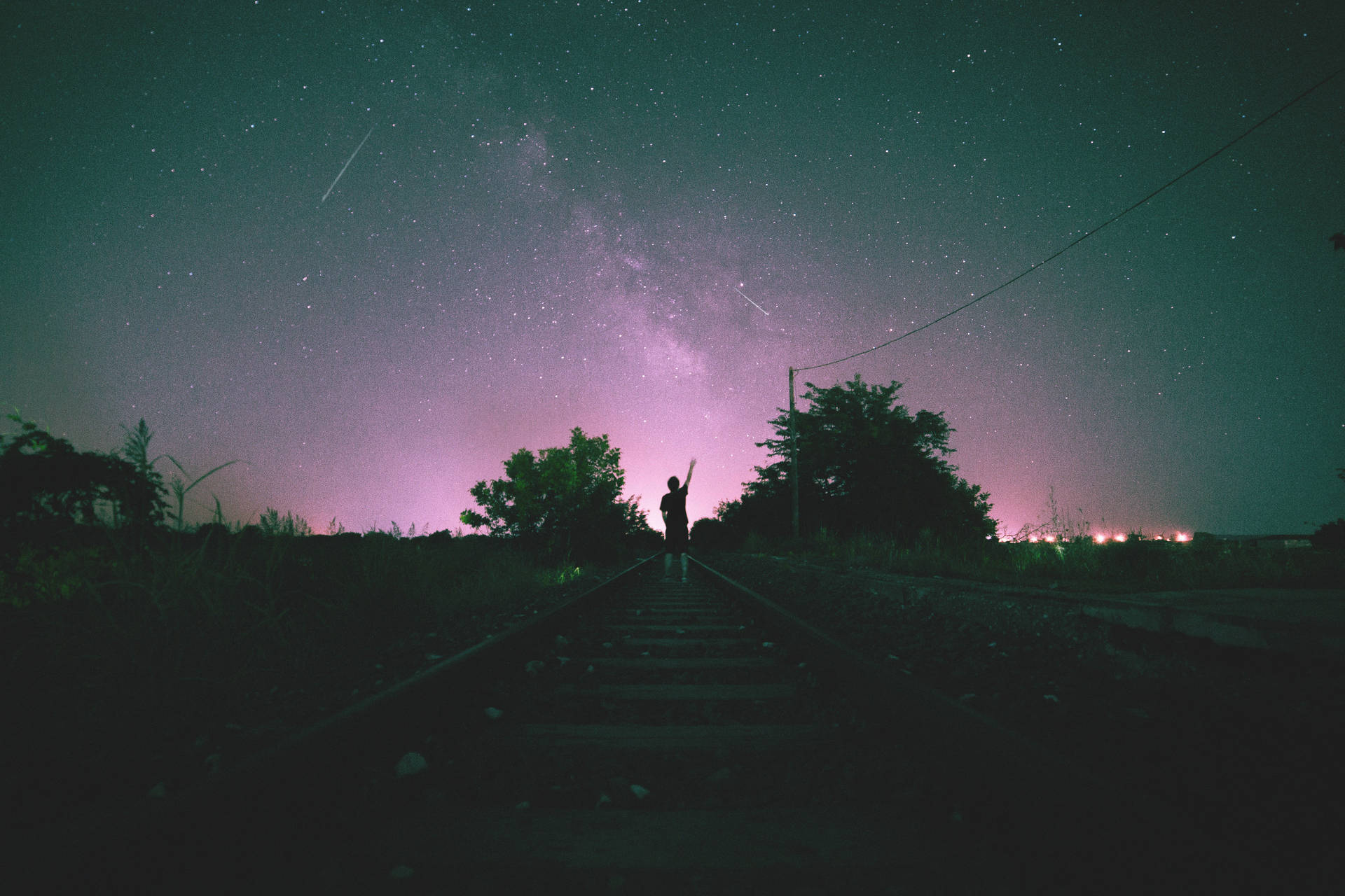 一個人的剪影站在火車軌道上，背景是星光燦爛的紫色夜空。