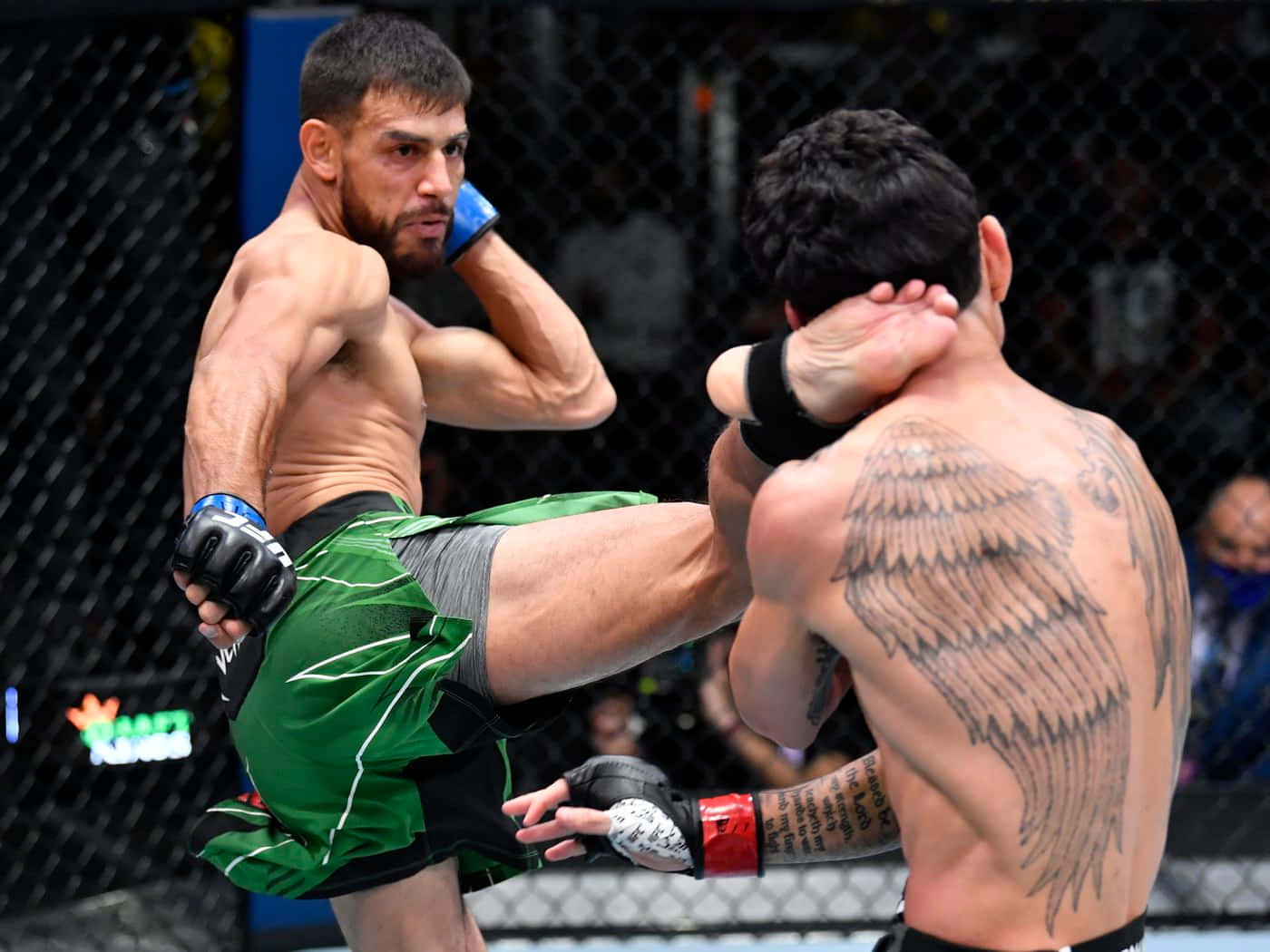 籠內兩名MMA拳手一人踢另一人有天使翅膀紋身