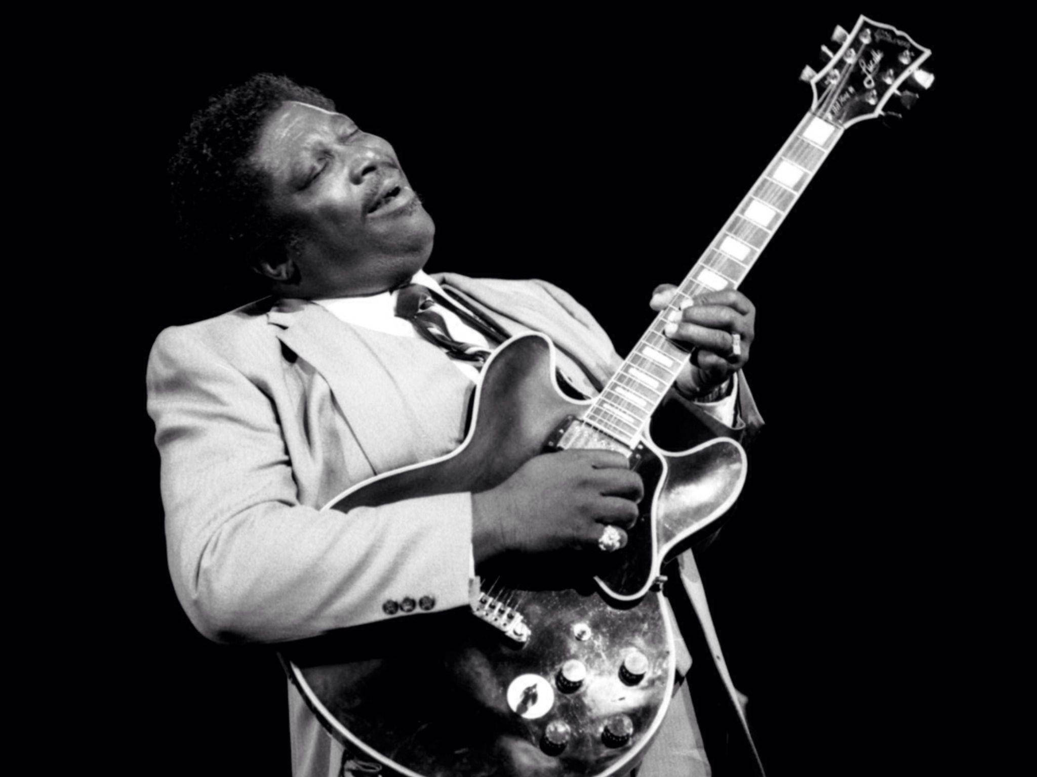 無可阻擋的藍調之王B.B. King 壁紙 — 一張黑白肖像，B.B. King 在深色背景下閉上眼睛熱情地彈奏結他。