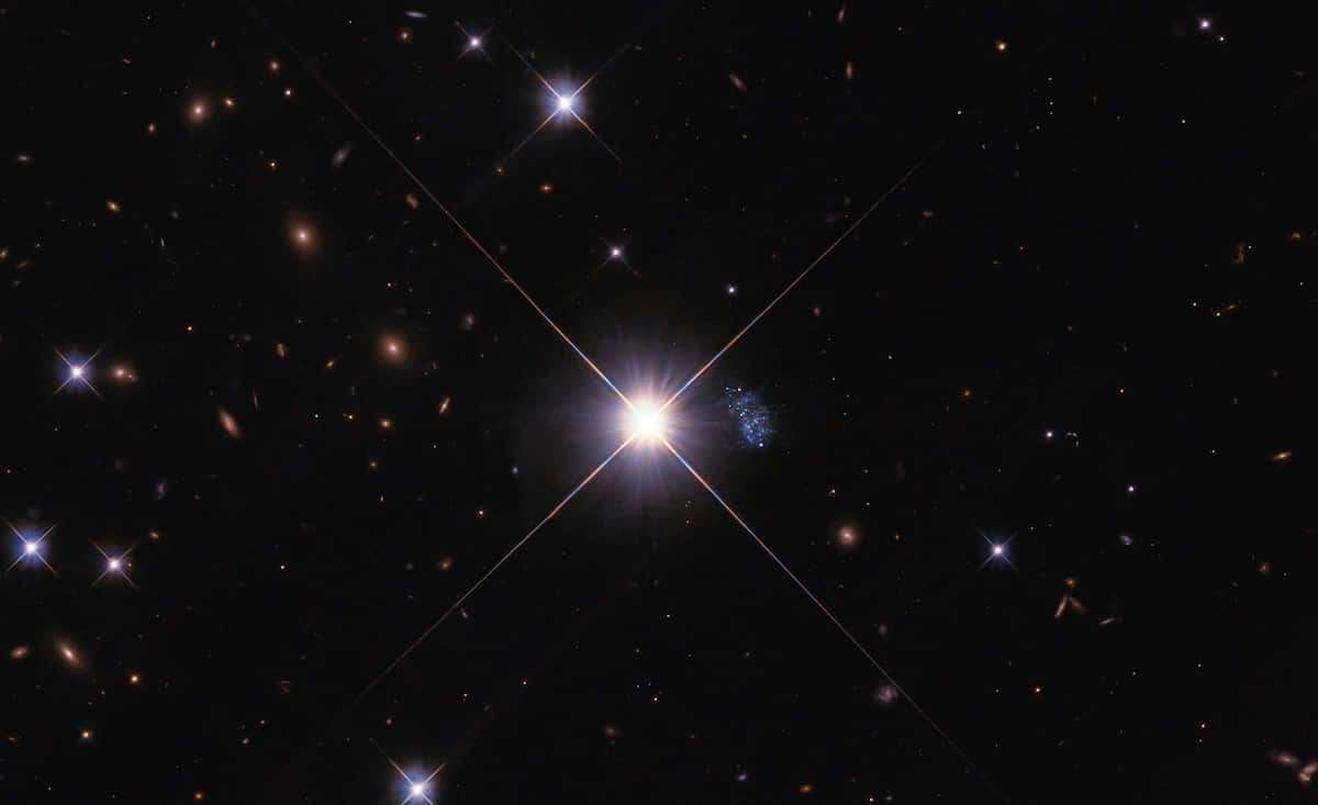 無垠星海的天象奇觀 壁紙 — 一顆璀璨的星星在深邃的黑色宇宙中閃耀著光芒，宇宙中點綴著遙遠的星系和微弱的星星。