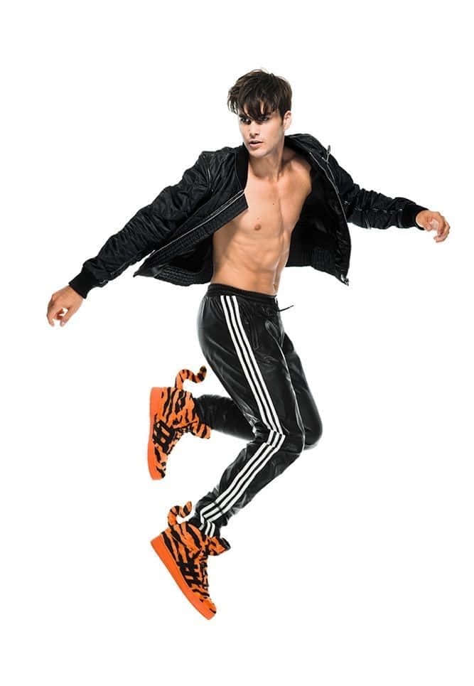 無懼！ 壁紙 — 一名赤裸上身的男子穿著黑色運動服和橙色老虎印花運動鞋，在純白色背景上動態跳躍。