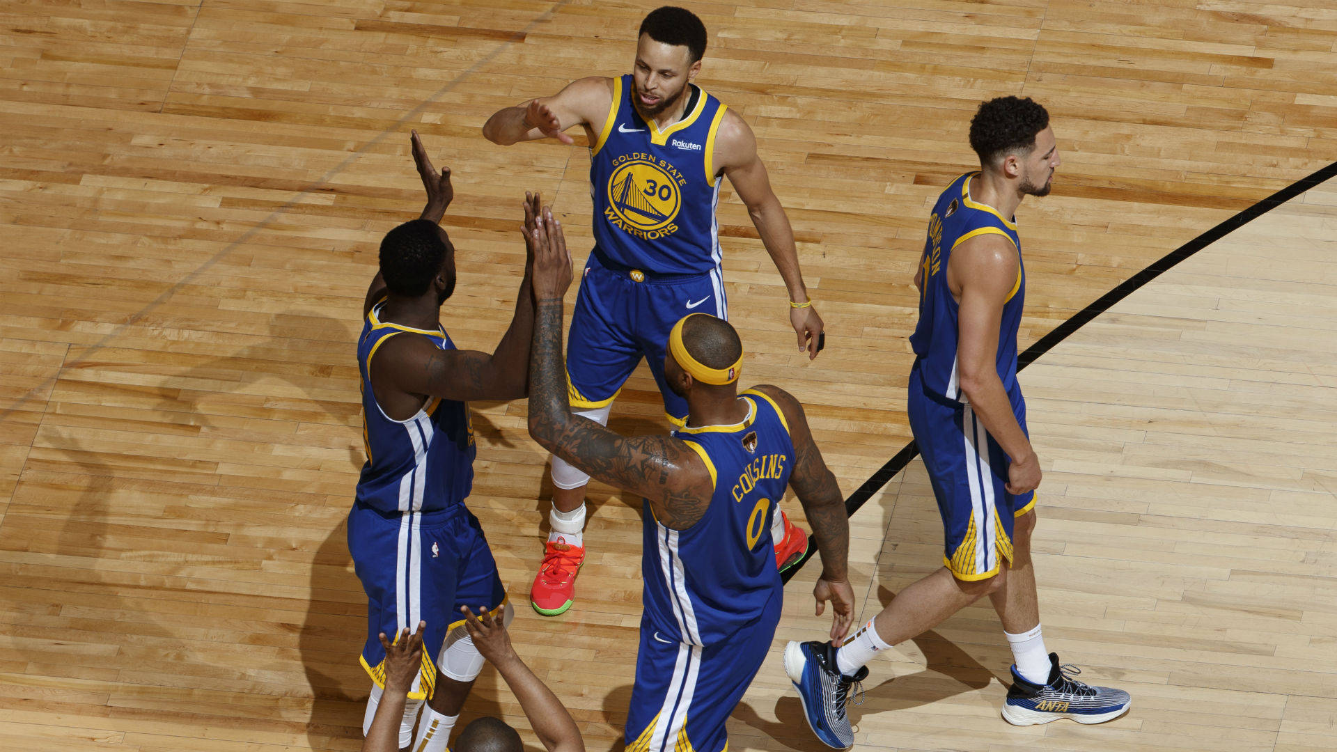 無敵勇士隊NBA總決賽 壁紙 — 金州勇士隊球員在拋光硬木球場上以擊掌和動態姿勢慶祝比賽。