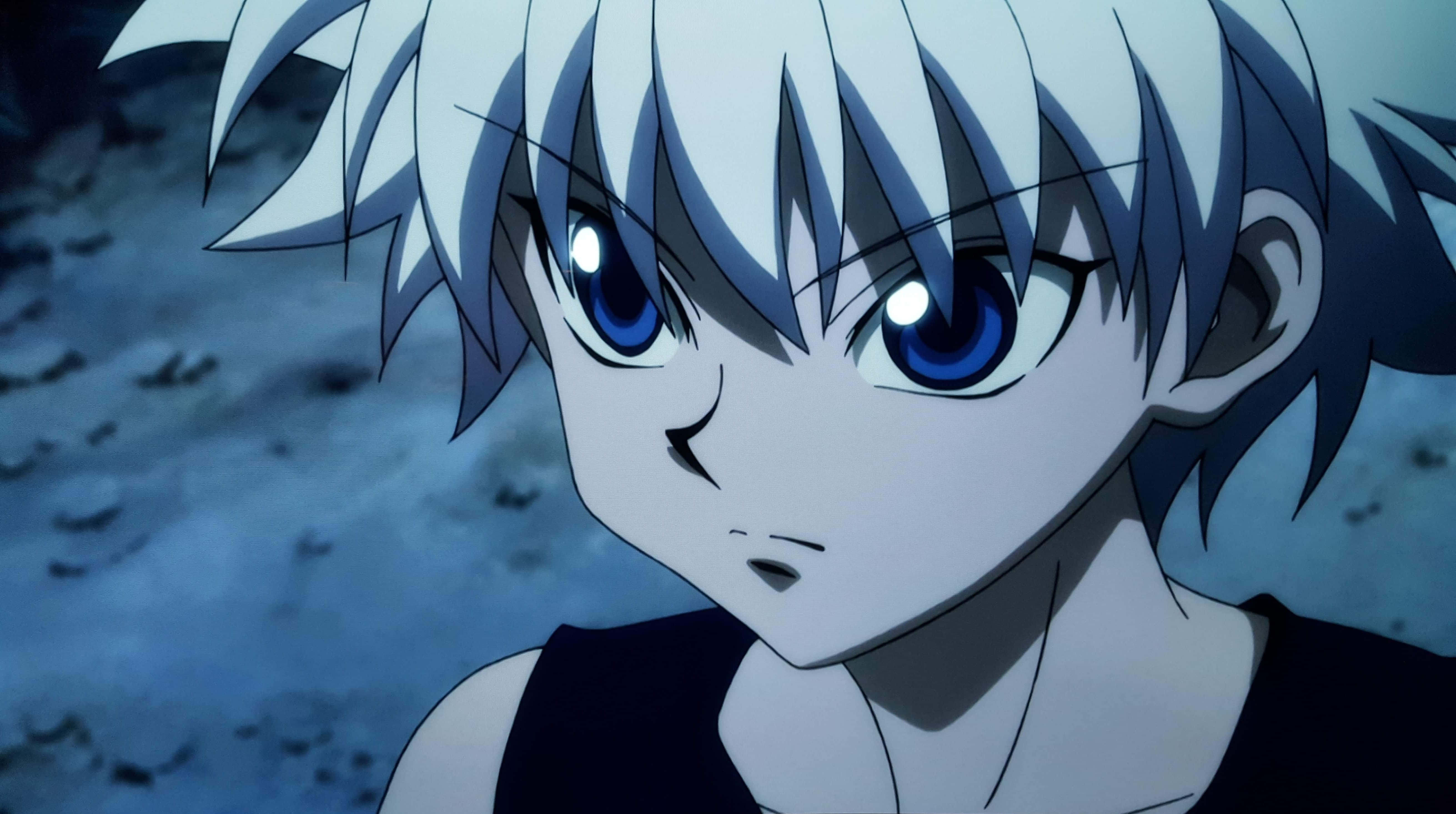 無畏刺客 - Killua Zoldyck 壁紙 — 一個動漫角色的特寫，擁有尖刺般的白色頭髮和強烈的藍色眼睛，在模糊的藍色背景前凝視前方。