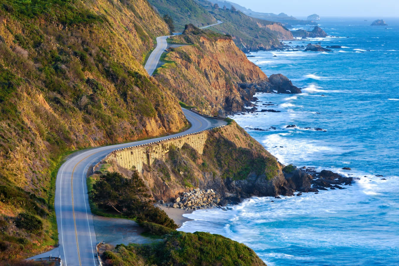 蜿蜒的海岸公路沿著懸崖，下方海浪在日落時分拍打。