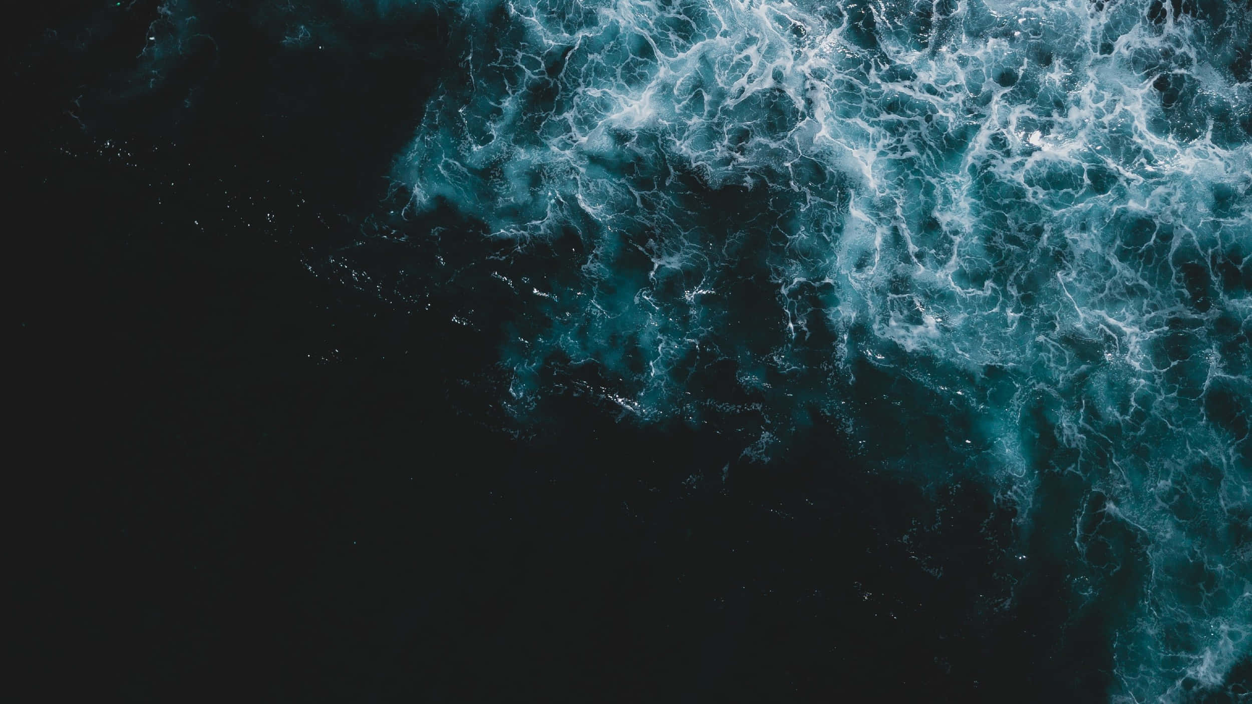 無盡海洋之美 壁紙 — 從空中俯瞰洶湧的海浪拍打深藍綠色海水，形成泡沫般的白色浪尖。