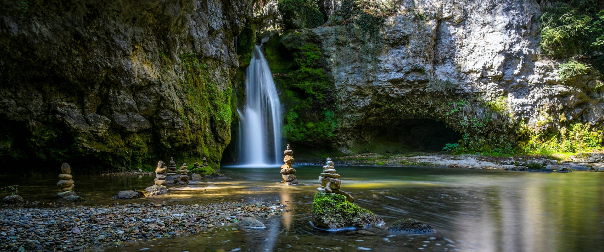 石堆在長滿苔蘚的峽谷中靠近寧靜的瀑布保持平衡。