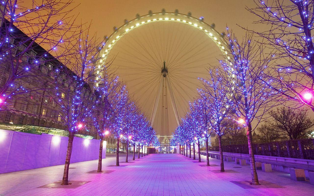 一條夜間步道，藍色燈光的樹木通向倫敦眼。
