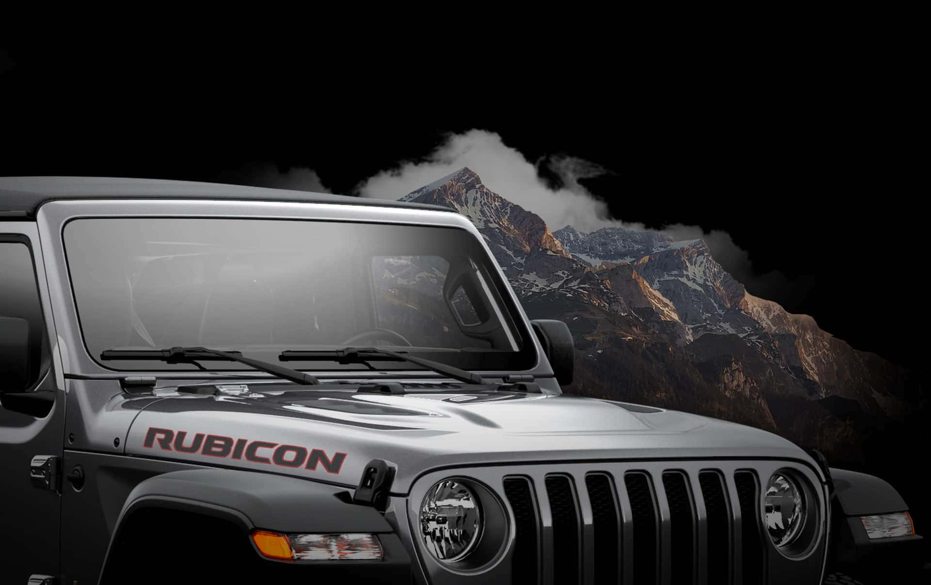 銀色Jeep Rubicon停在黑暗天空下的雪山前。