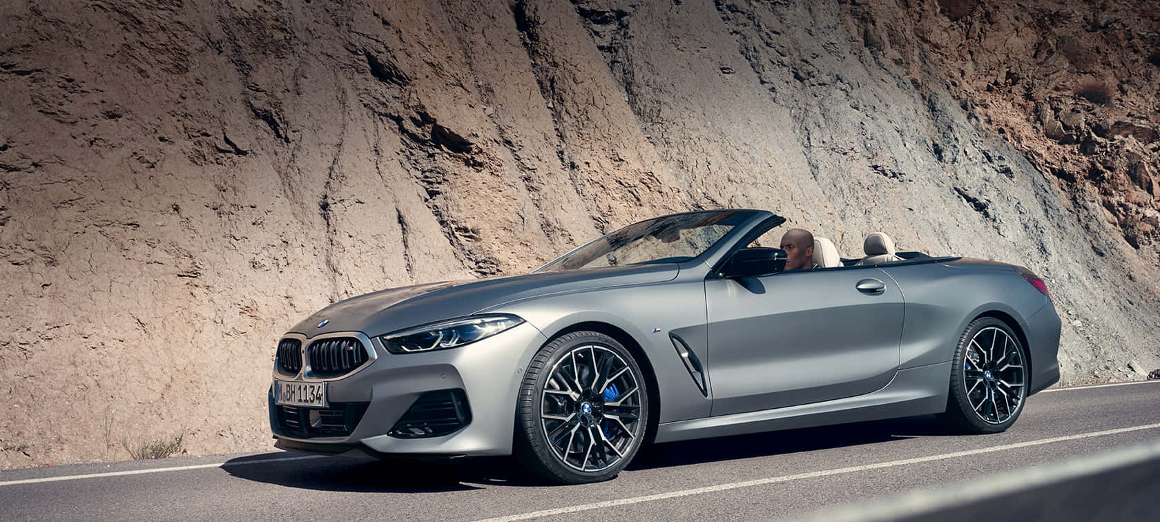無論何種駕駛，BMW始終提供平順體驗 壁紙 — 一架時尚的銀色寶馬開篷車沿著蜿蜒的山路行駛，司機享受著開篷駕駛的樂趣。
