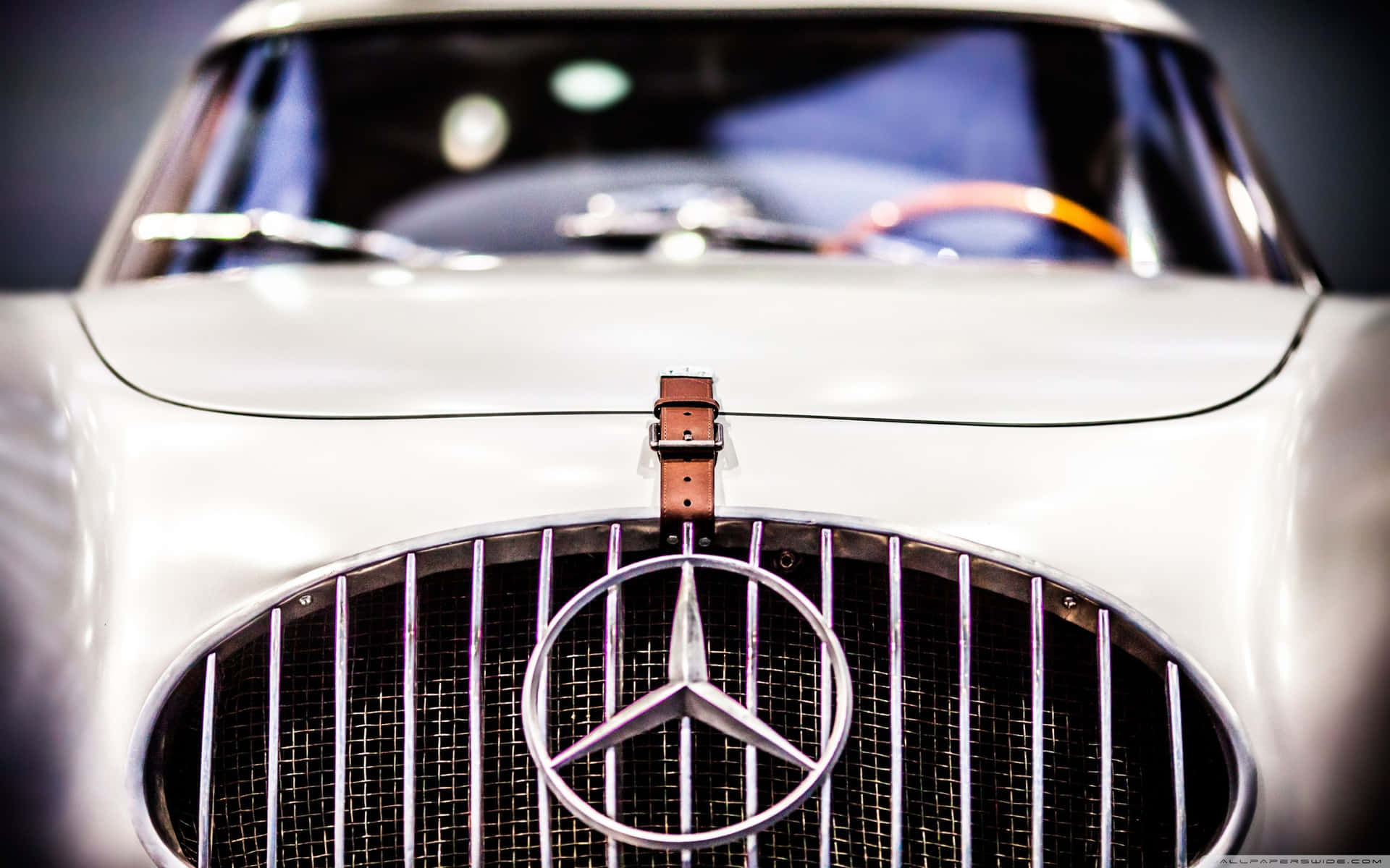 經典白色 Mercedes-Benz 汽車格柵近距離特寫，帶有鍍鉻標誌和皮革帶。
