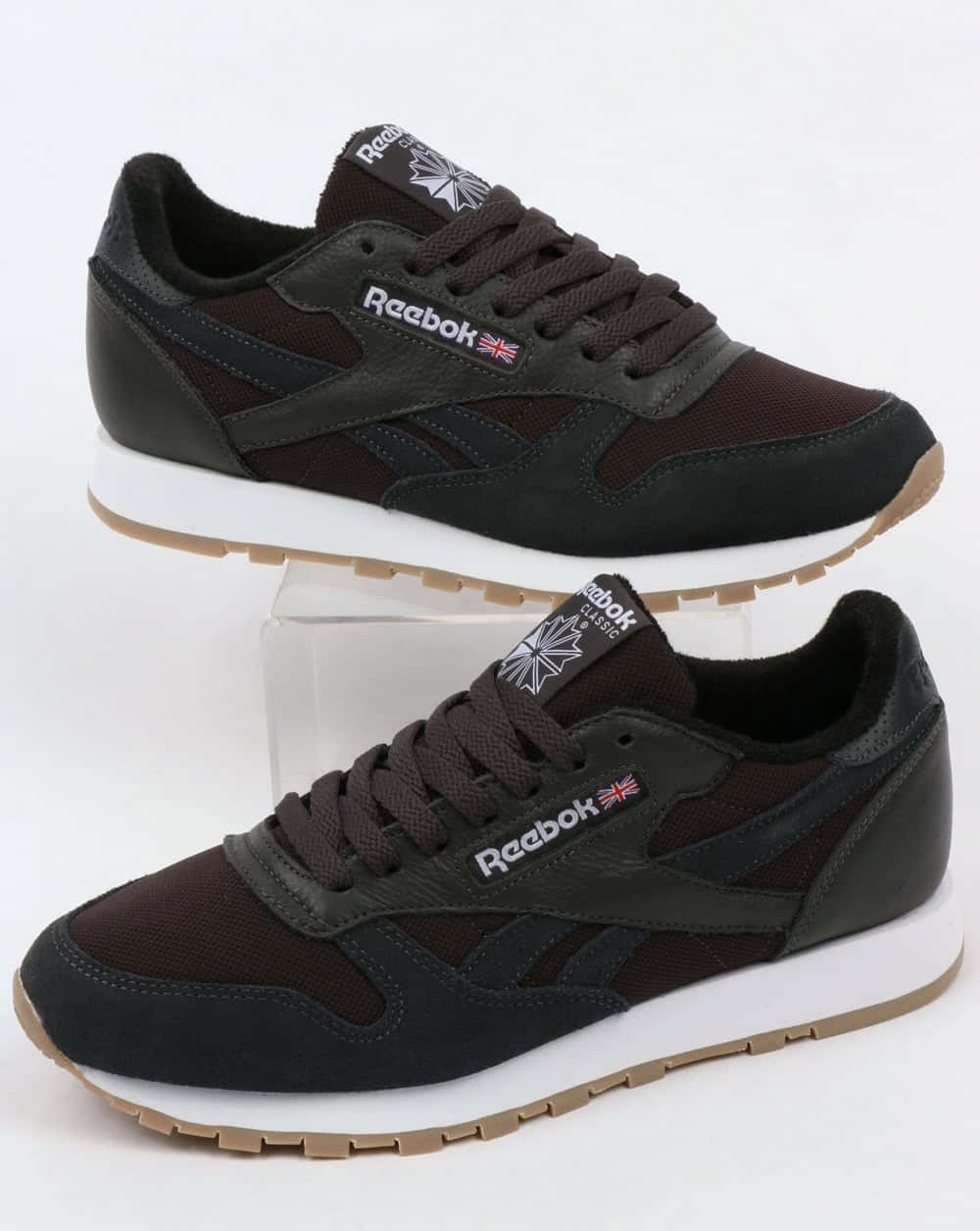 無論季節如何，保持健康活力 壁紙 — 兩雙深棕色 Reebok Classic 運動鞋，白色鞋底，展示在透明支架上，背景為純白色。
