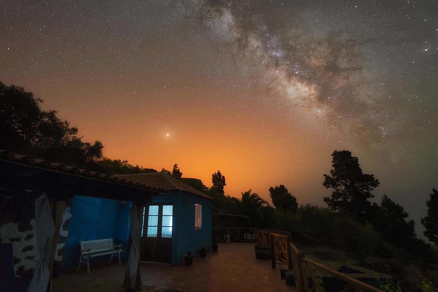藍色房子在星空下發光的窗戶，伴隨著銀河。