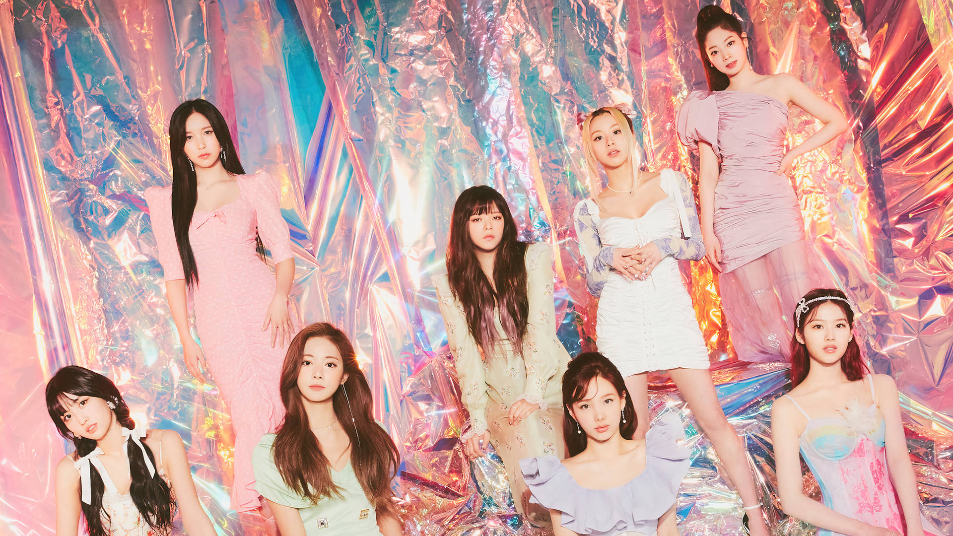 無酒精 TWICE 4K 海報 壁紙 — 七位身穿粉彩連衣裙的女性在閃爍的彩虹色箔紙背景前自信地擺姿勢。