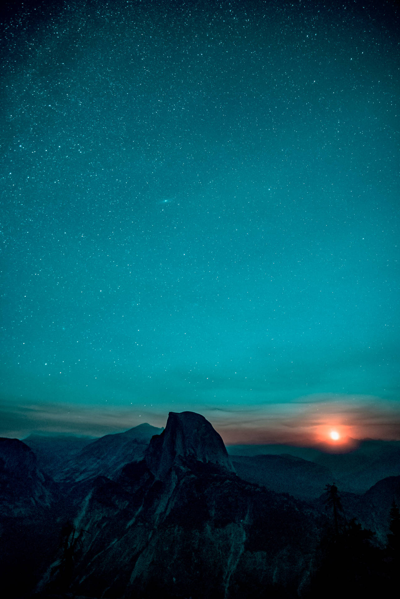 在青綠色星空下的山峰，橙色夕陽落在遠山之後。