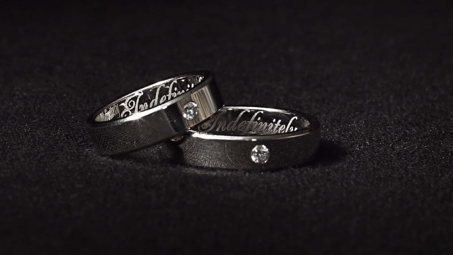 黑色背景上兩枚刻有鑽石的結婚戒指。