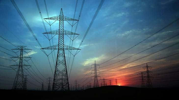 輸電塔在鮮豔的日落天空下形成剪影。