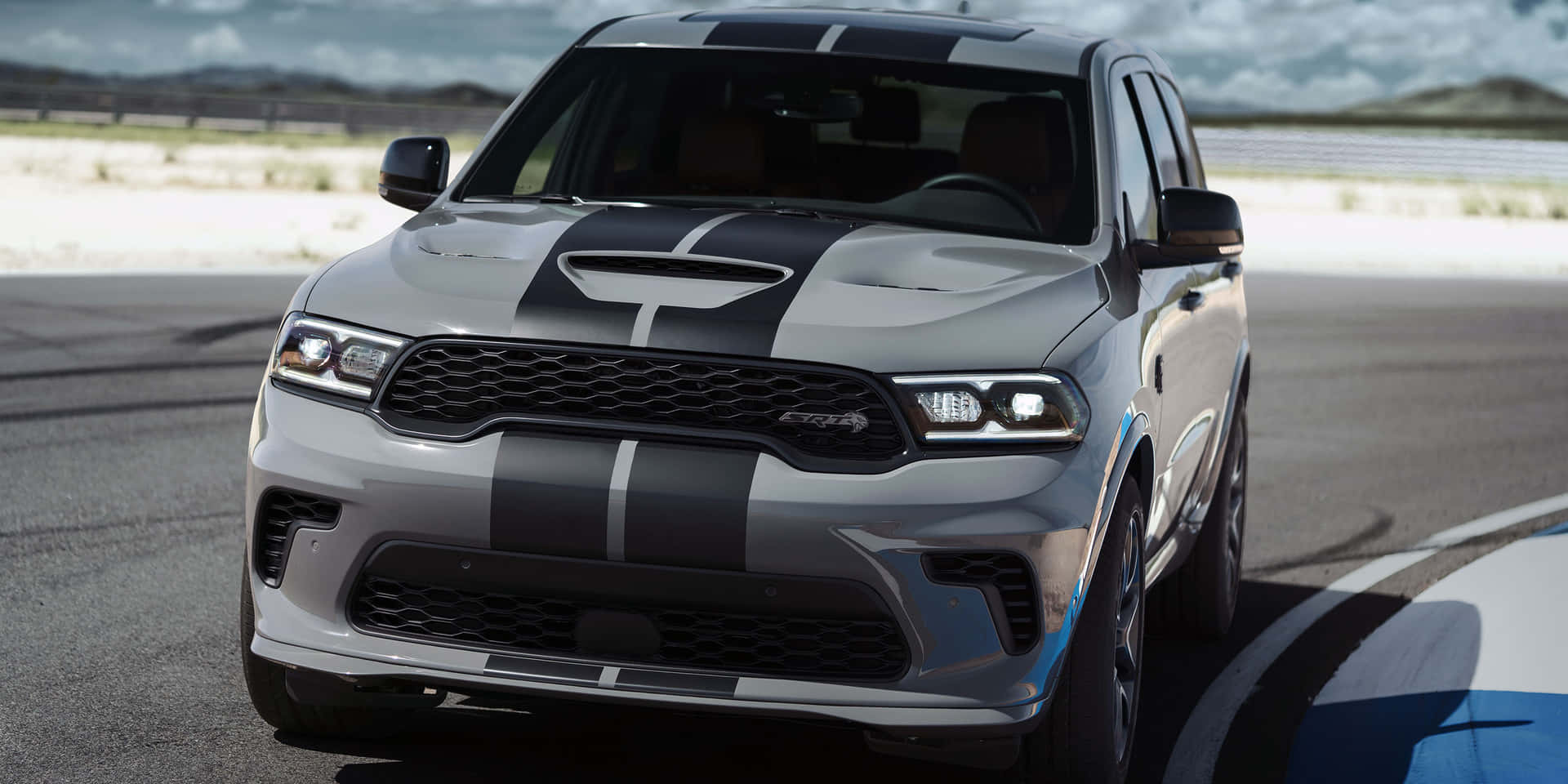 銀色Dodge Durango SRT帶有黑色賽車條紋在賽道上。