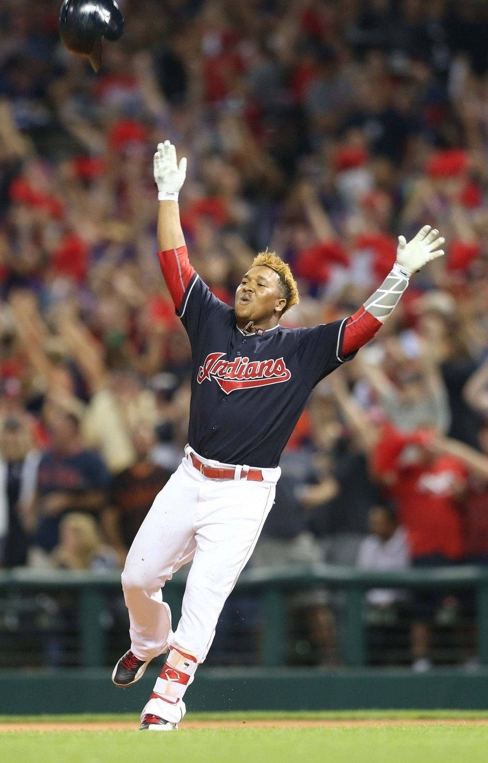 無頭盔 Jose Ramirez 壁紙 — 一名身穿深藍色印第安人隊球衣的棒球選手在夜間比賽中，高舉雙臂、頭盔拋向空中，歡欣跳躍。